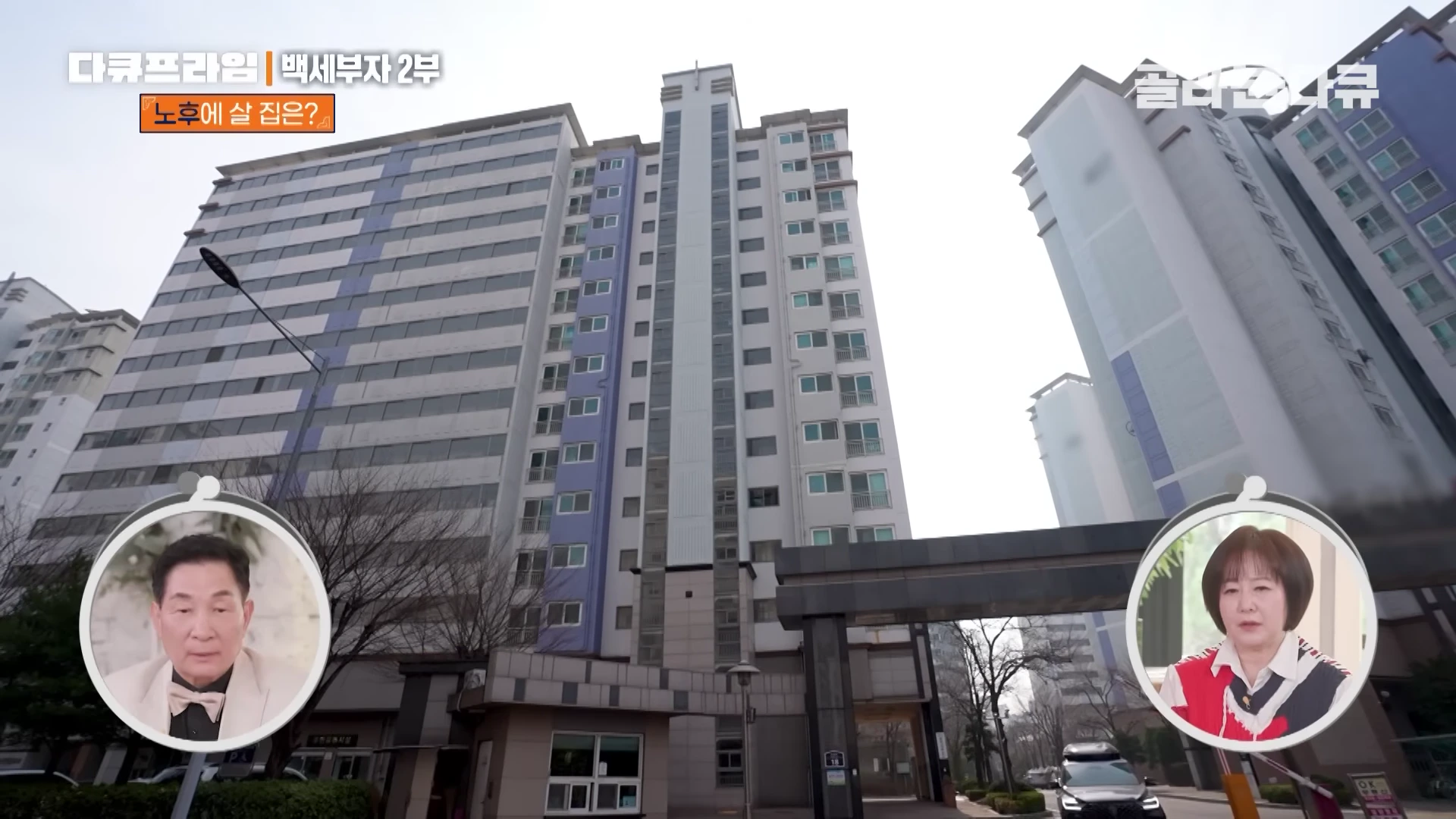 고층 아파트 단지가 보이고 화면 하단 좌우에는 인터뷰하는 남녀의 얼굴이 원형 테두리로 삽입되어 있습니다.