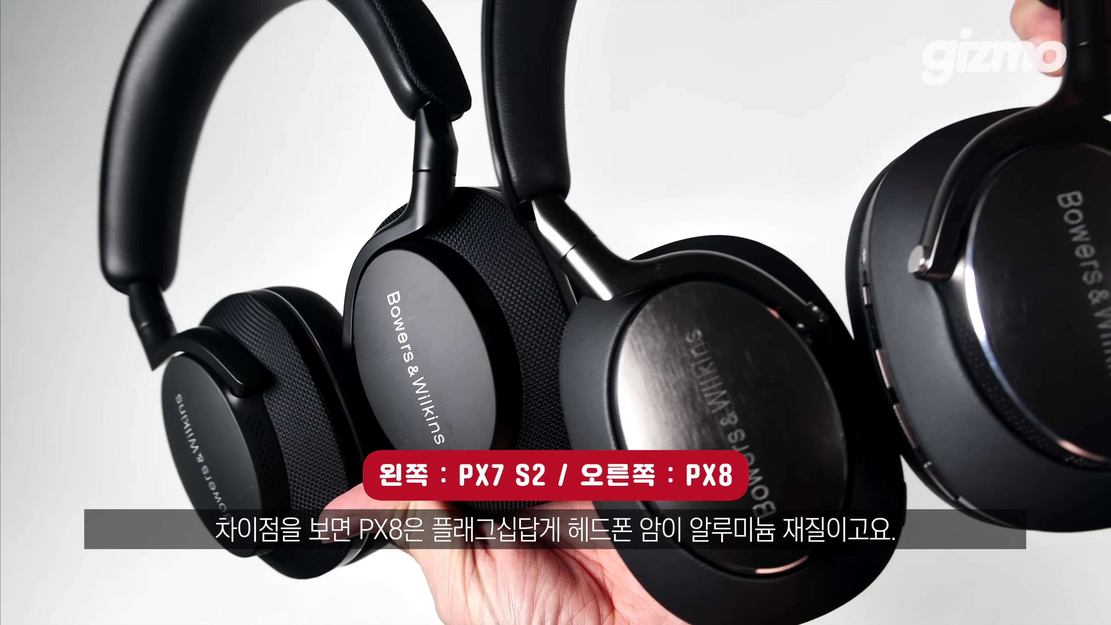 두 개의 B&W 무선 헤드폰을 손으로 들고 있는 모습.