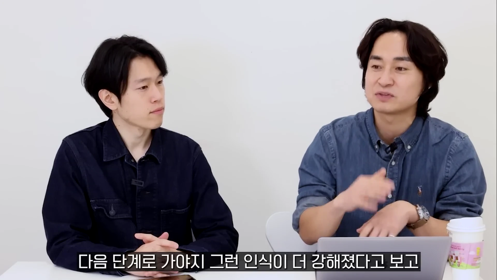 두 남자가 밝은 실내에서 이야기를 나누며 대화하는 모습