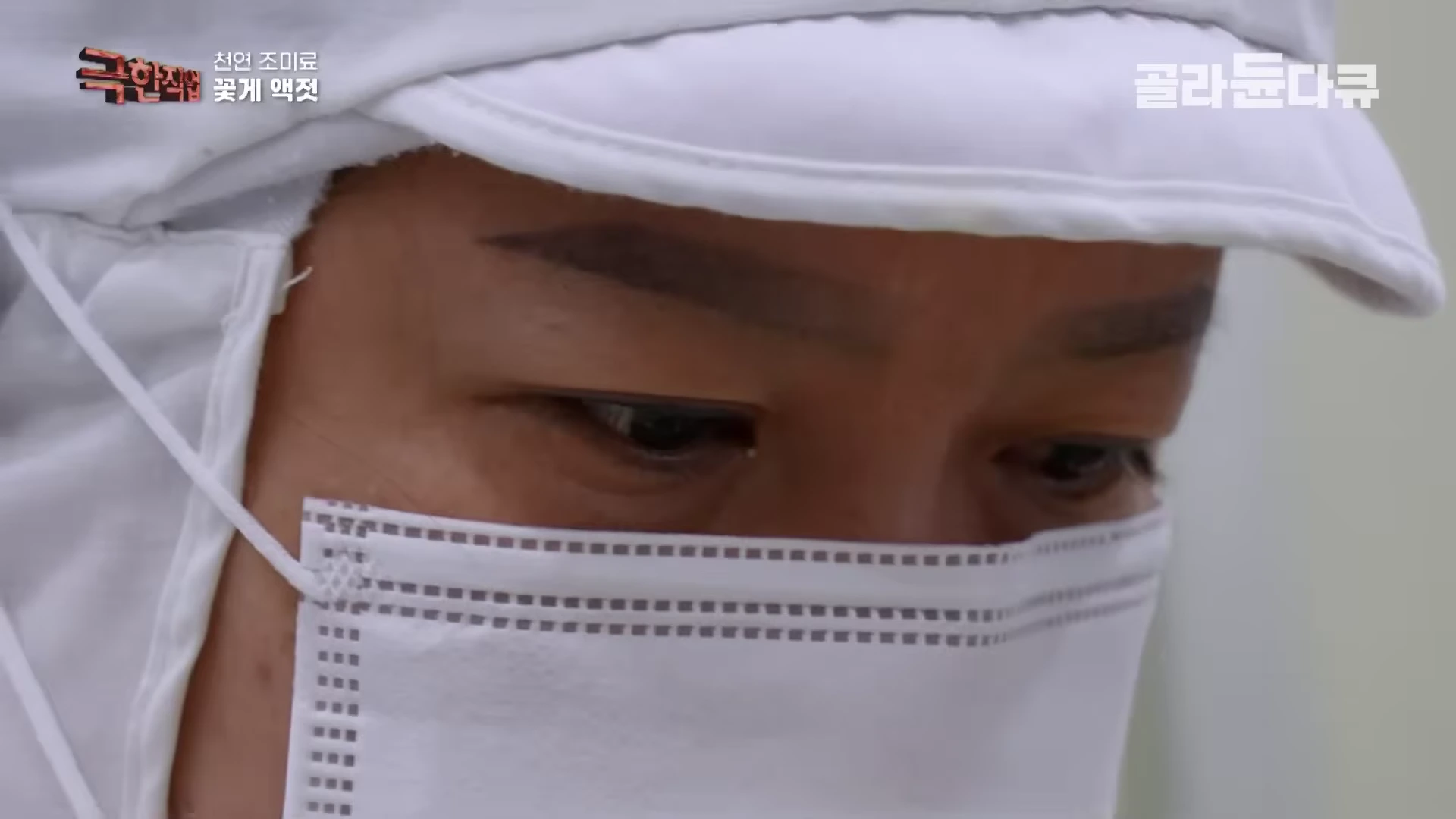 흰색 위생 모자와 마스크를 착용한 작업자가 눈을 내리깔고 꽃게 손질에 집중하고 있는 모습