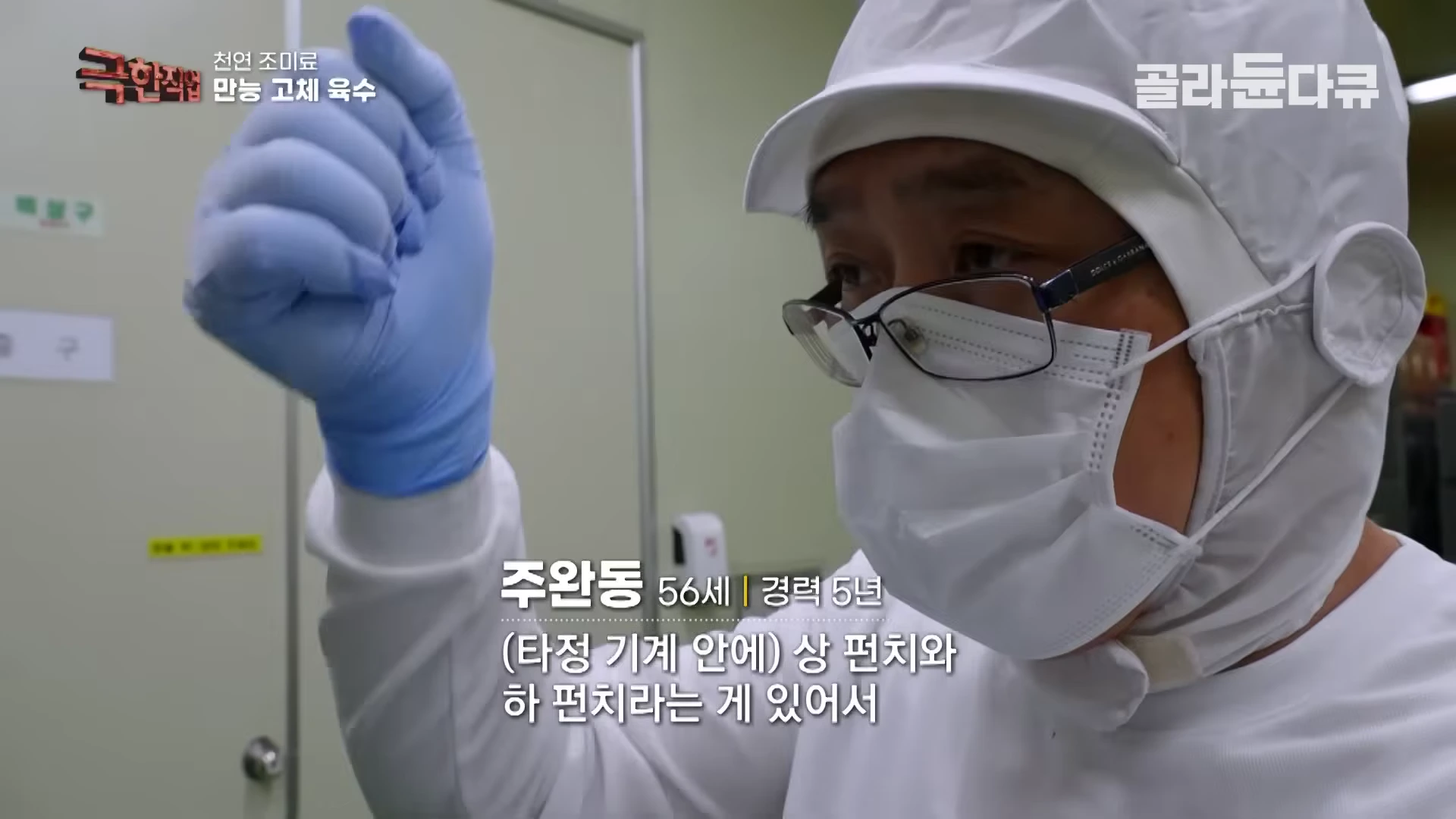 위생복과 마스크를 착용한 작업자가 손동작으로 기계의 원리를 설명하고 있다.