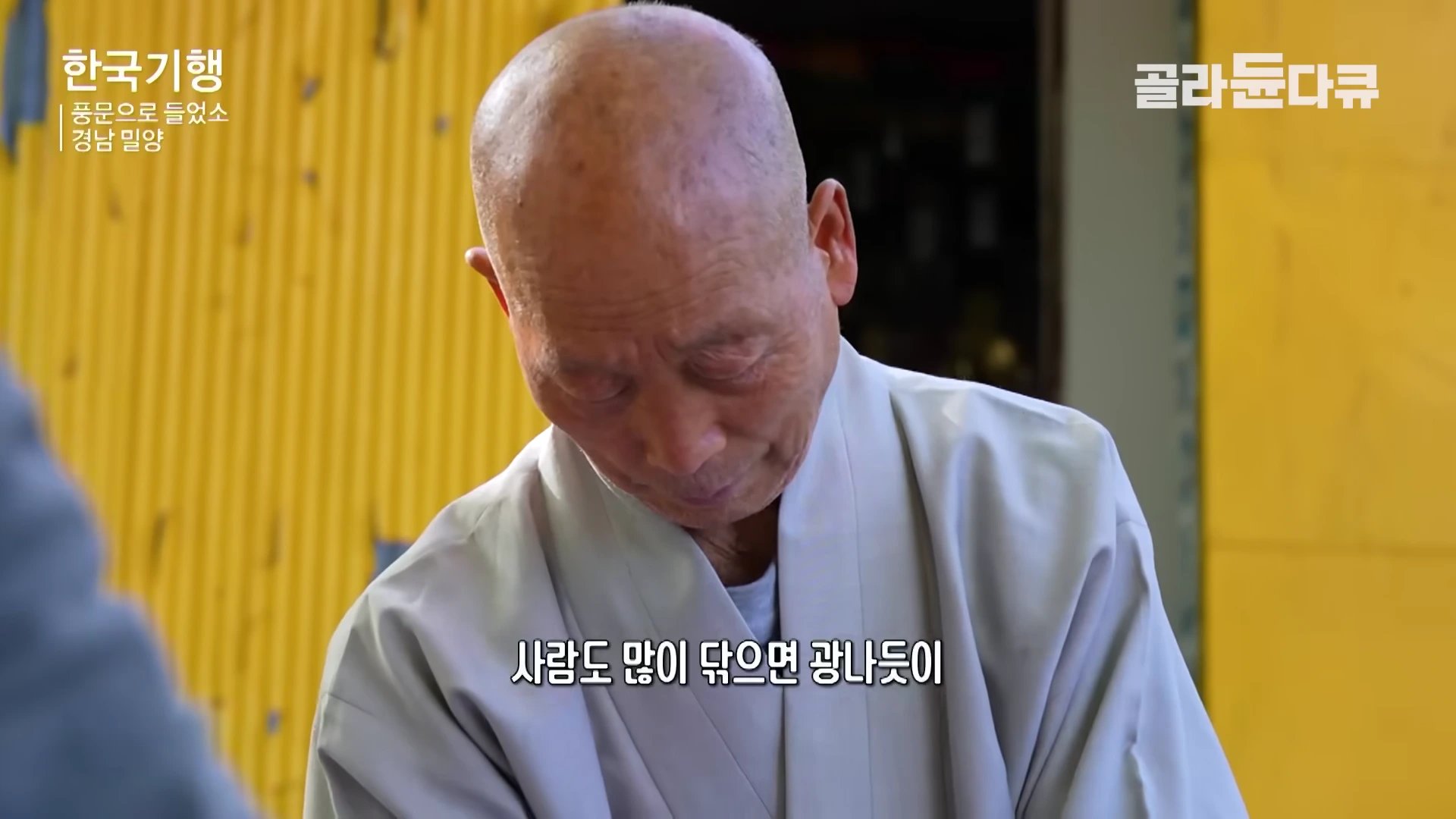 회색 승복을 입은 스님이 고개를 숙이고 무언가를 닦으며 수행에 집중하고 있는 모습