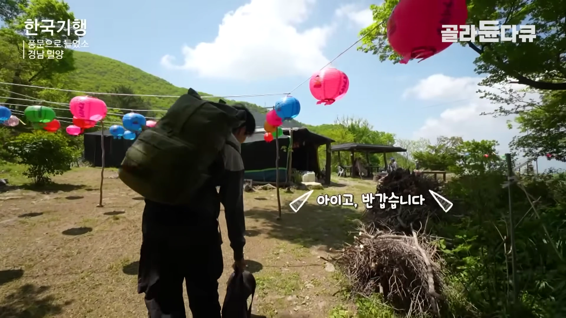 등산 배낭을 멘 사람이 연등이 줄지어 걸린 산속 암자 마당으로 걸어 들어오고 있다.