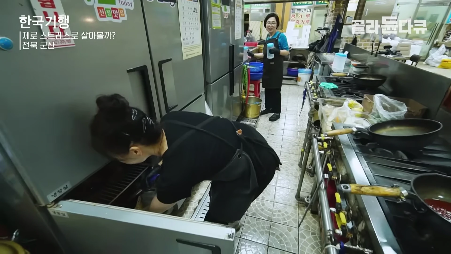 앞치마를 두른 두 명의 여성이 음식점 주방에서 재료를 준비하고 있는 모습