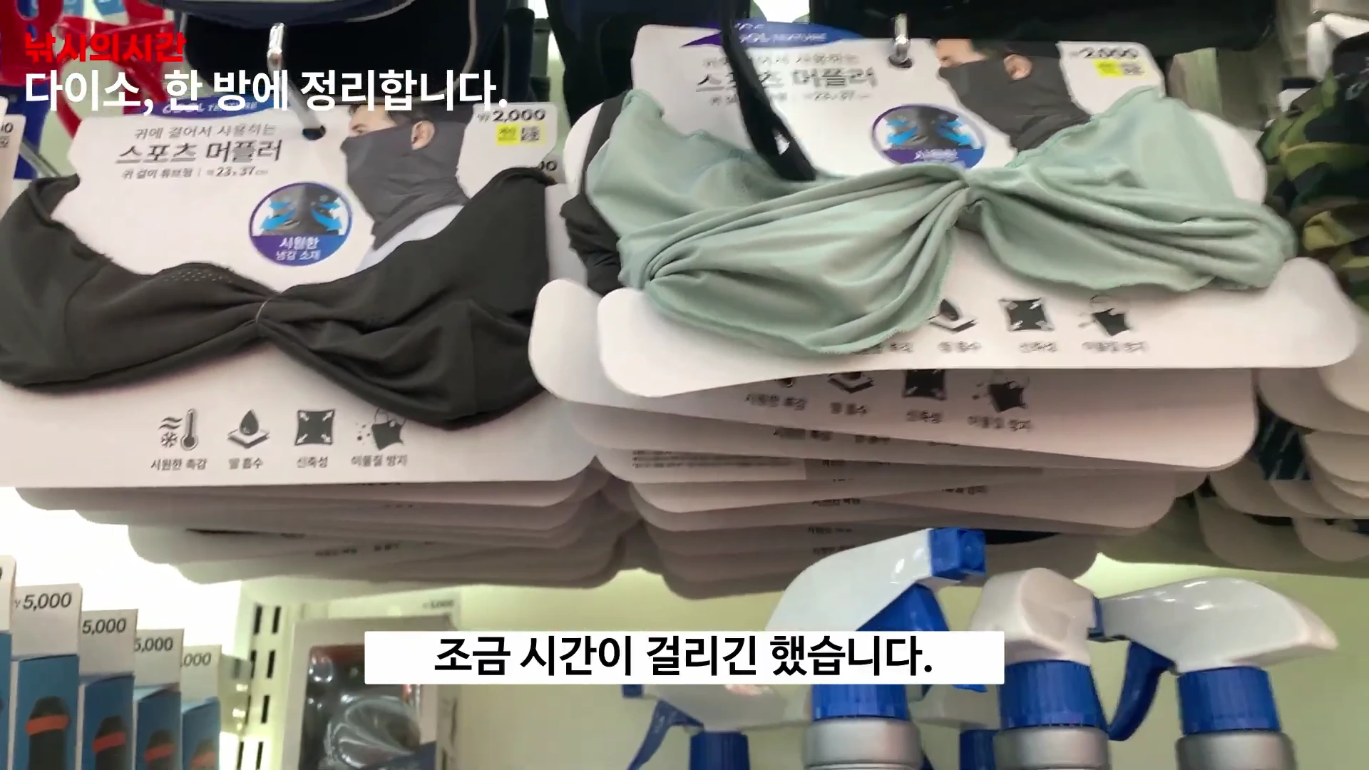 다이소 매장 진열대에 걸려 있는 낚시용품 겸용 스포츠 머플러 제품들과 그 아래로 각종 스프레이 병들이 배치되어 있는 모습.