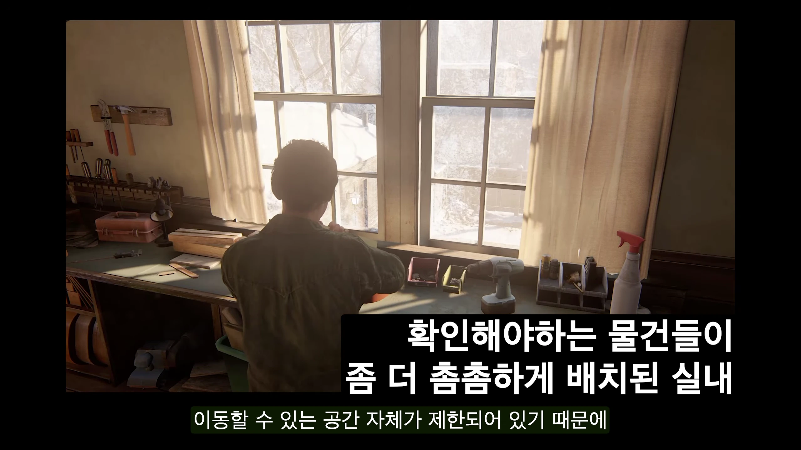 게임 속 실내 공간에서 캐릭터가 작업대 앞 창문을 향해 서 있는 뒷모습을 담은 3인칭 시점의 영상 캡처 화면.