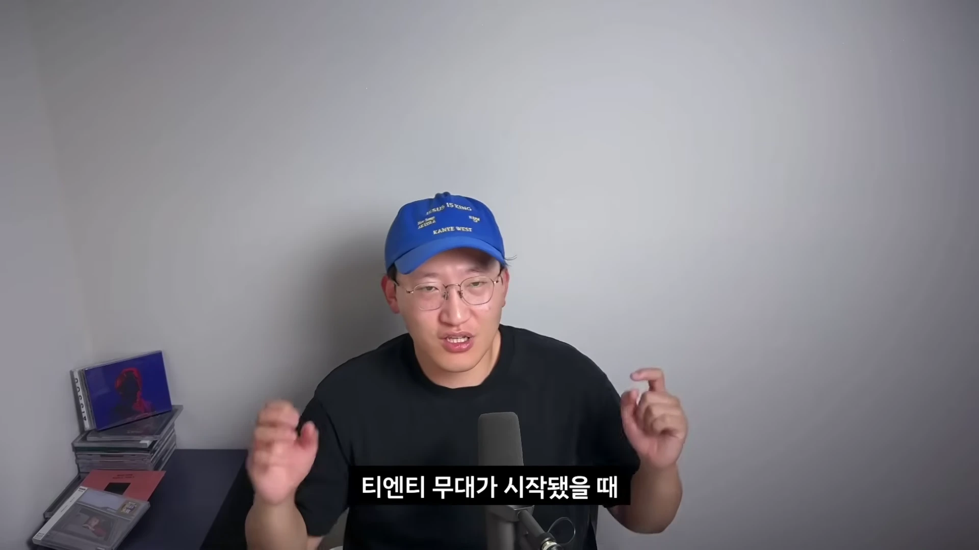 파란색 야구 모자와 안경을 쓴 남성이 마이크 앞에서 대화하고 있으며, 화면 하단에는 흰색 자막이 배치되어 있습니다.