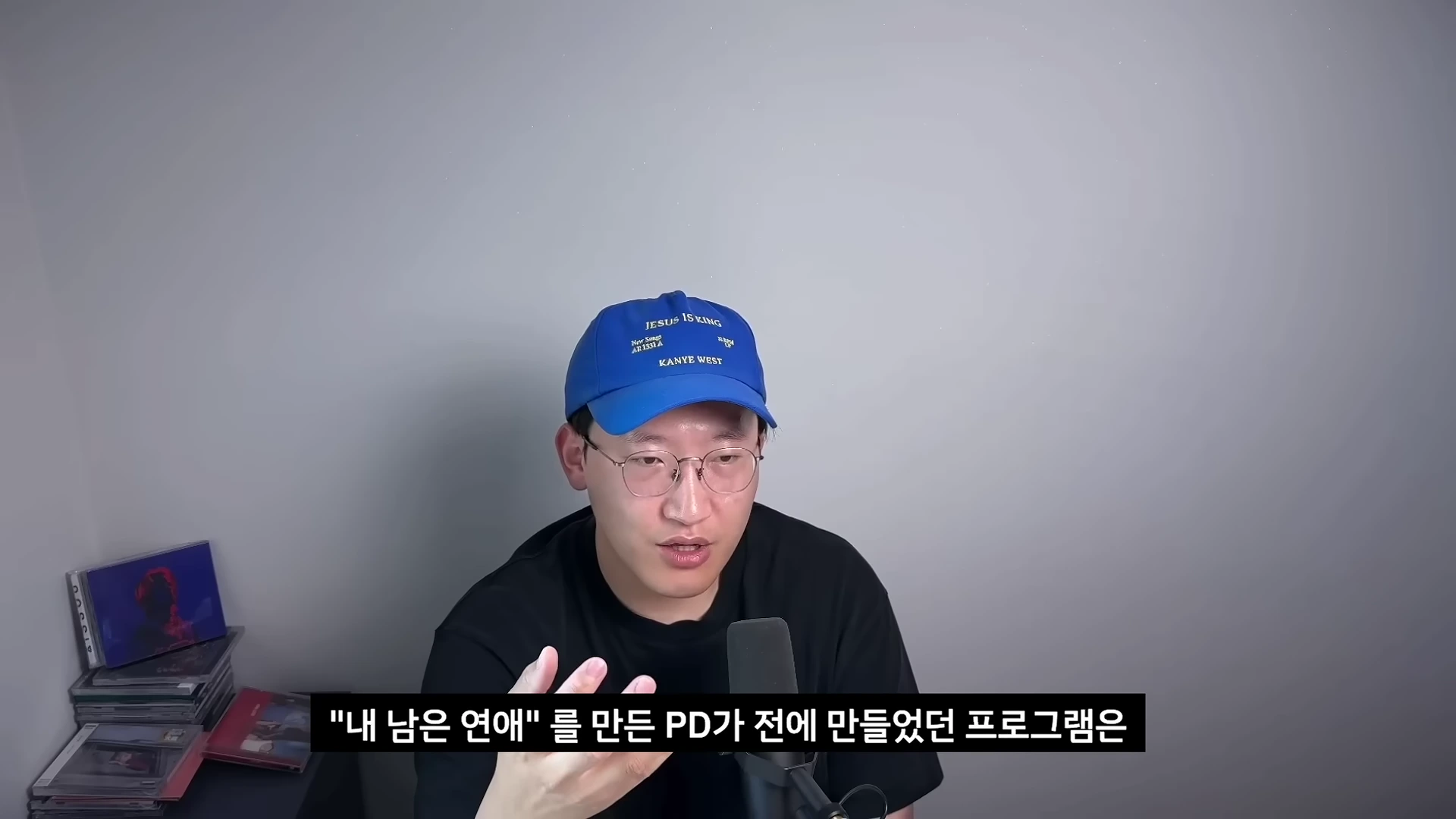 파란색 야구 모자를 쓰고 안경을 쓴 남성이 마이크 앞에 앉아 이야기를 하고 있으며, 하단에는 한국어 자막이 표시되어 있습니다.