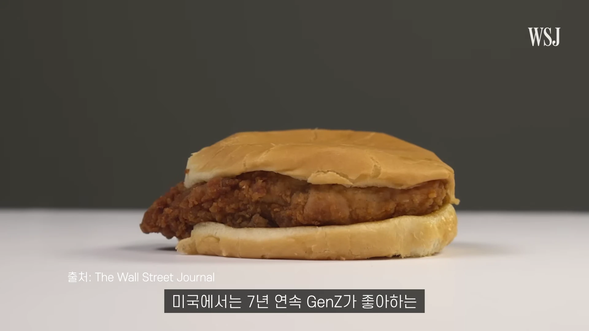 흰색 배경 중앙에 놓인 심플한 치킨 버거의 근접 사진