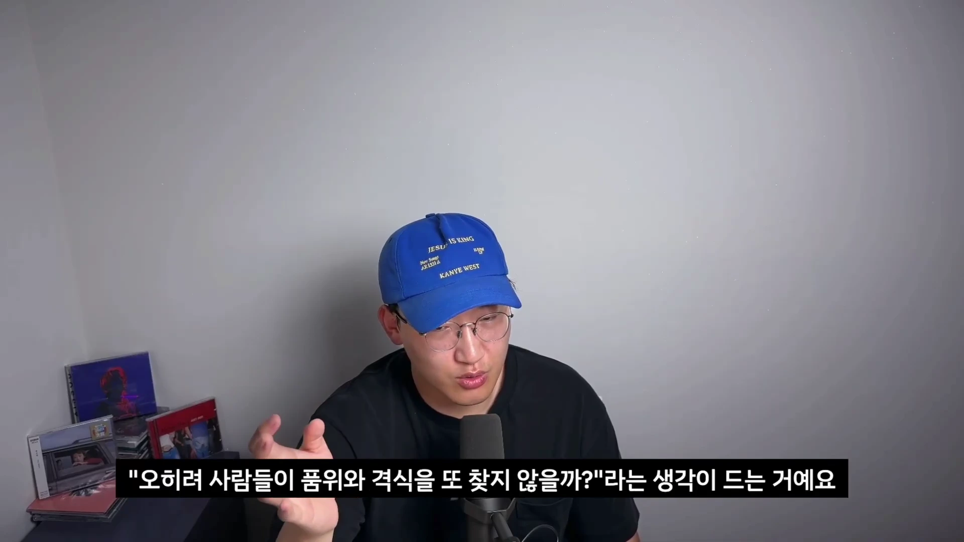 파란색 야구 모자를 쓴 남성이 마이크 앞에 앉아 손짓하며 대화하는 모습과 하단에 한국어 자막이 있는 화면