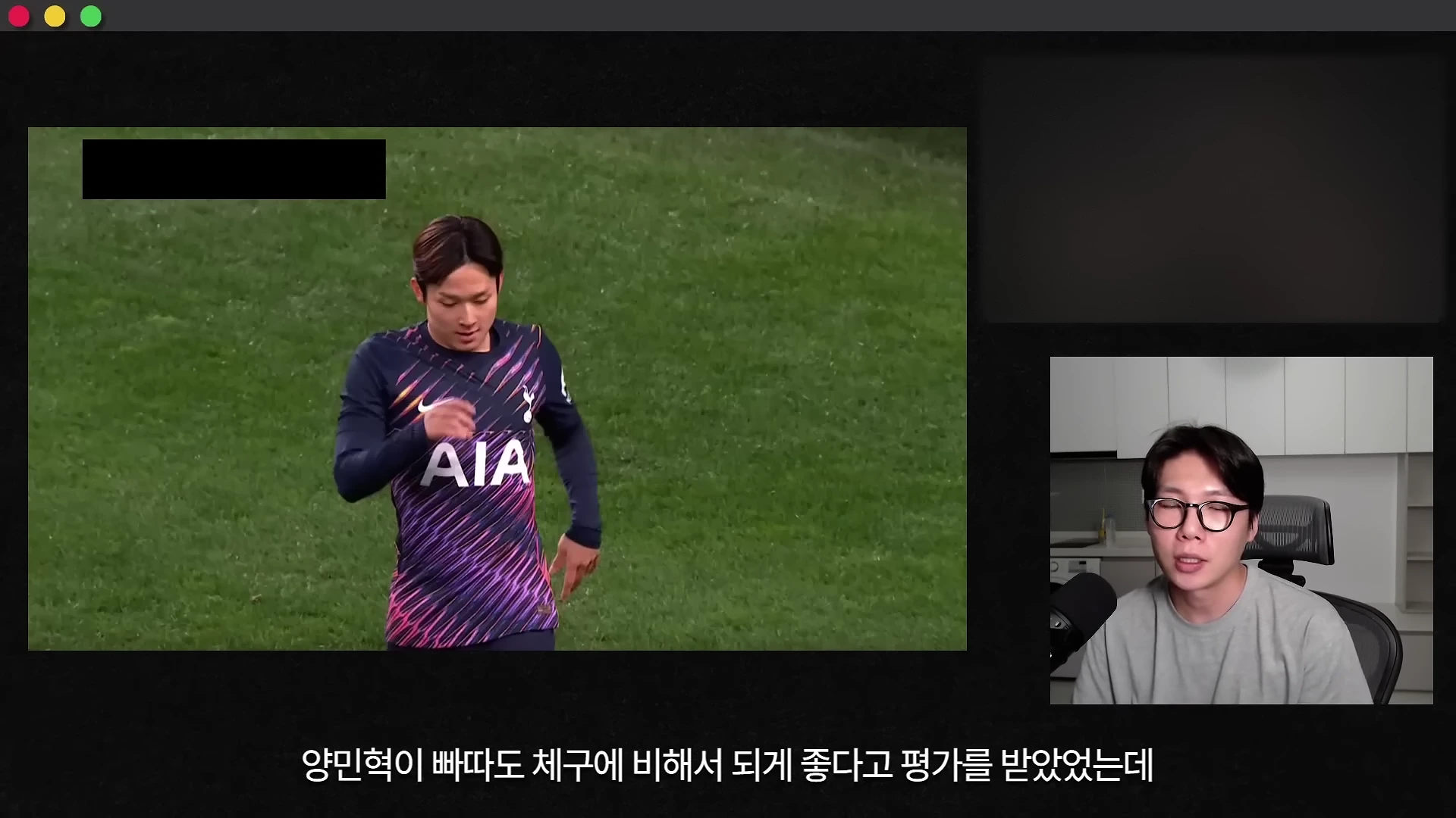축구 유니폼을 입은 선수가 경기장에서 걸어가고 있으며, 오른쪽 하단에는 안경을 쓴 남성이 마이크 앞에서 이야기하는 영상 캡처 화면