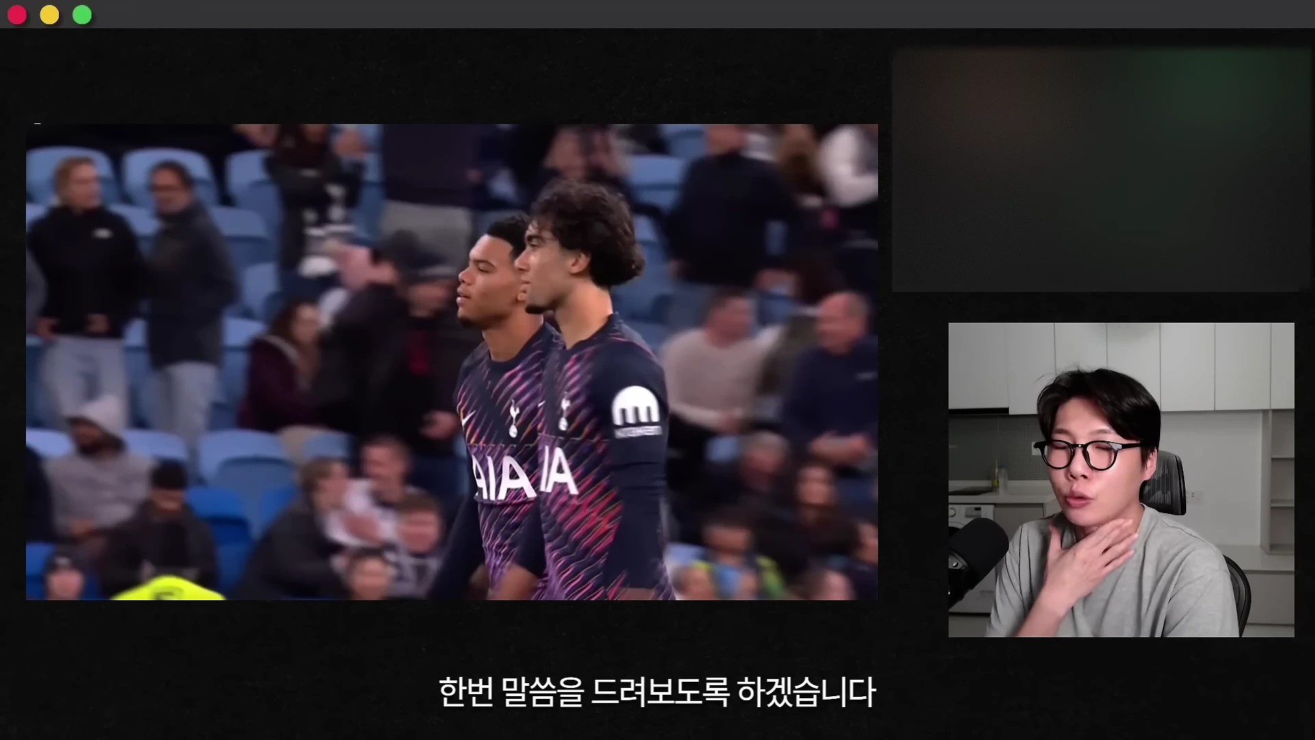 축구 경기 영상을 배경으로 화면 오른쪽 하단에 안경을 쓴 남성이 마이크 앞에서 이야기하고 있는 모습입니다.