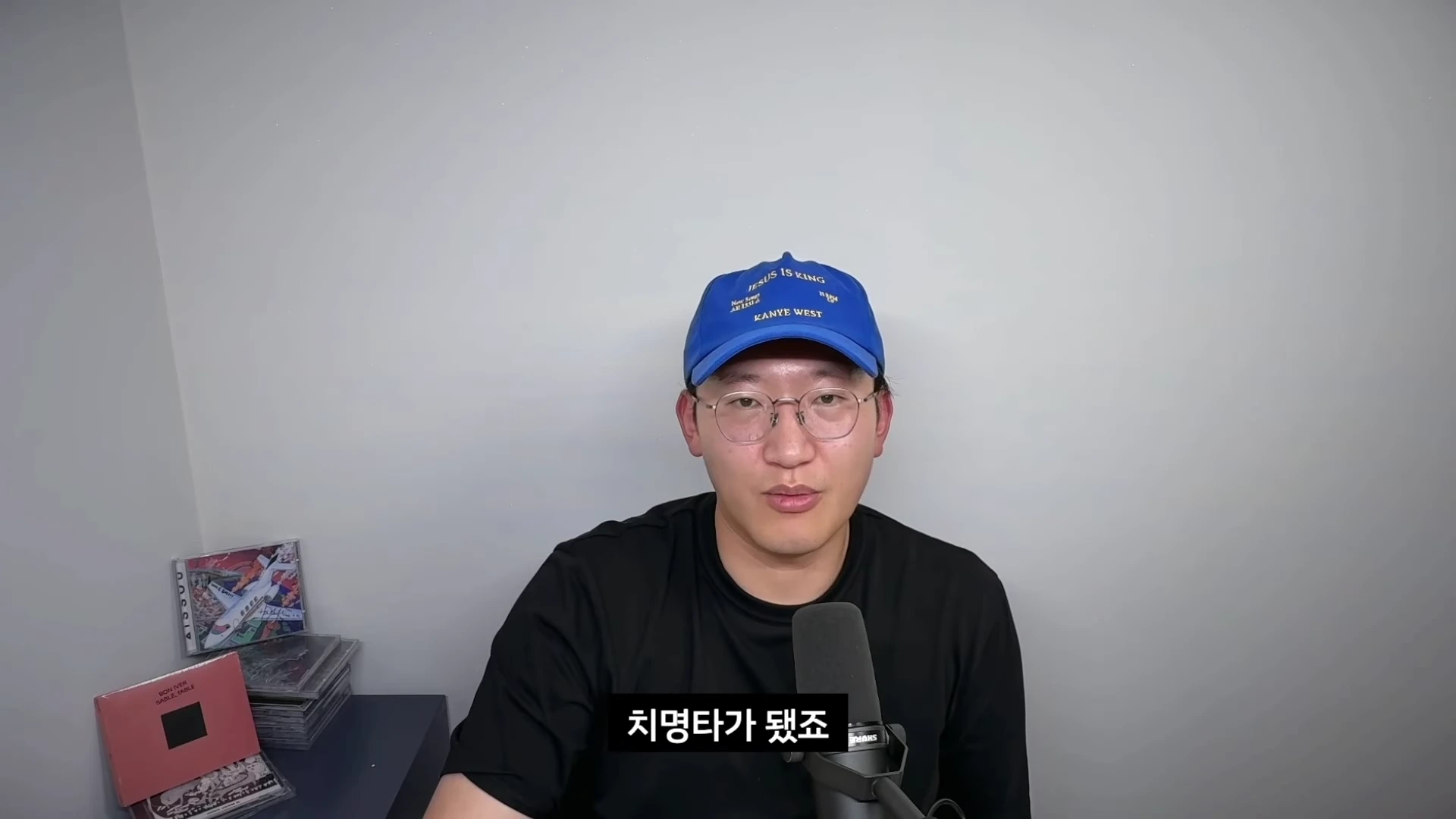 파란색 야구 모자와 안경을 쓴 남성이 마이크 앞에서 이야기하고 있으며 하단에 '치명타가 됐죠'라는 자막이 표시된 영상 캡처 화면입니다.