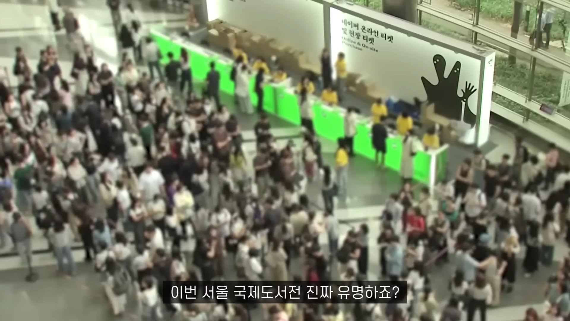 실내 행사장의 높은 곳에서 아래를 내려다본 모습으로 수많은 인파가 티켓 발매기 앞에 길게 줄을 서 있다.