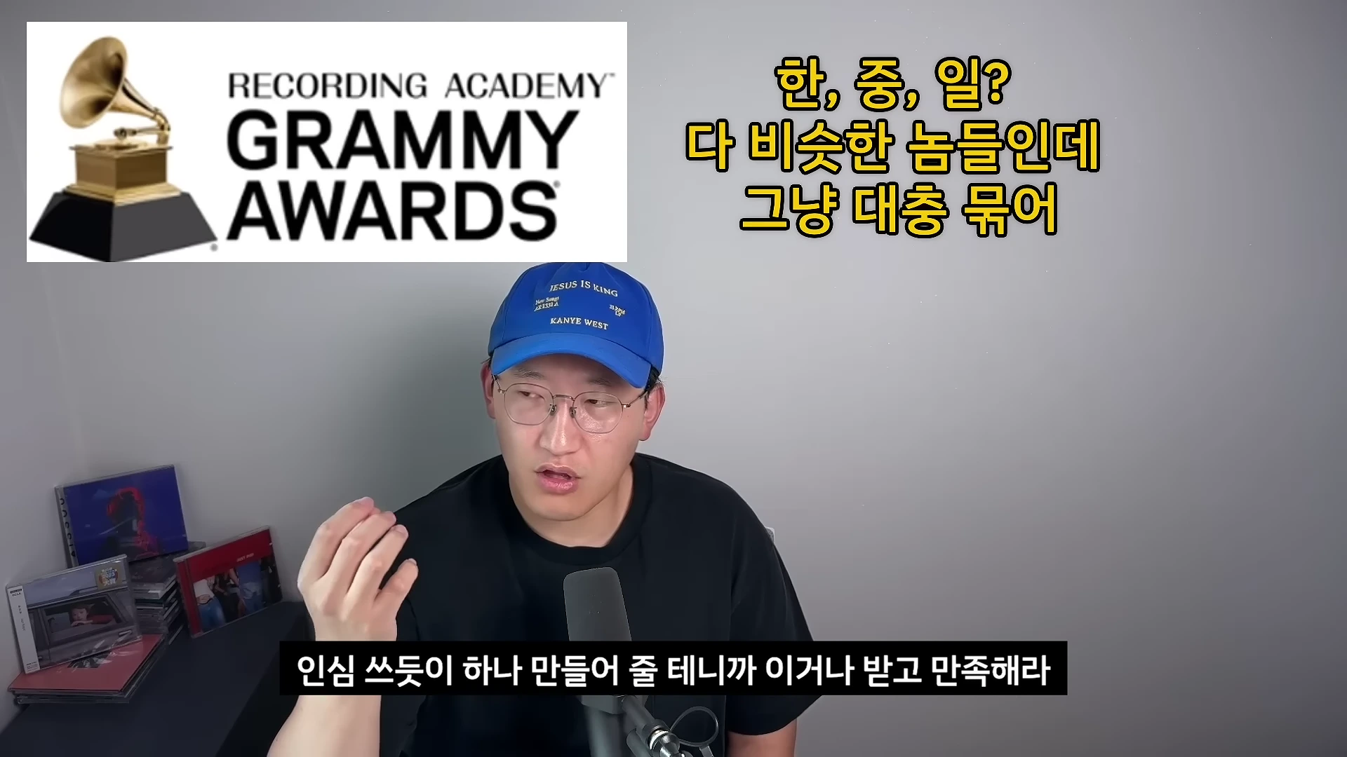 파란색 야구 모자를 쓴 안경 낀 남성이 마이크 앞에 앉아 이야기를 나누고 있으며, 화면 왼쪽 상단에는 그래미 어워드 로고가, 오른쪽 상단에는 자막이 배치되어 있습니다.