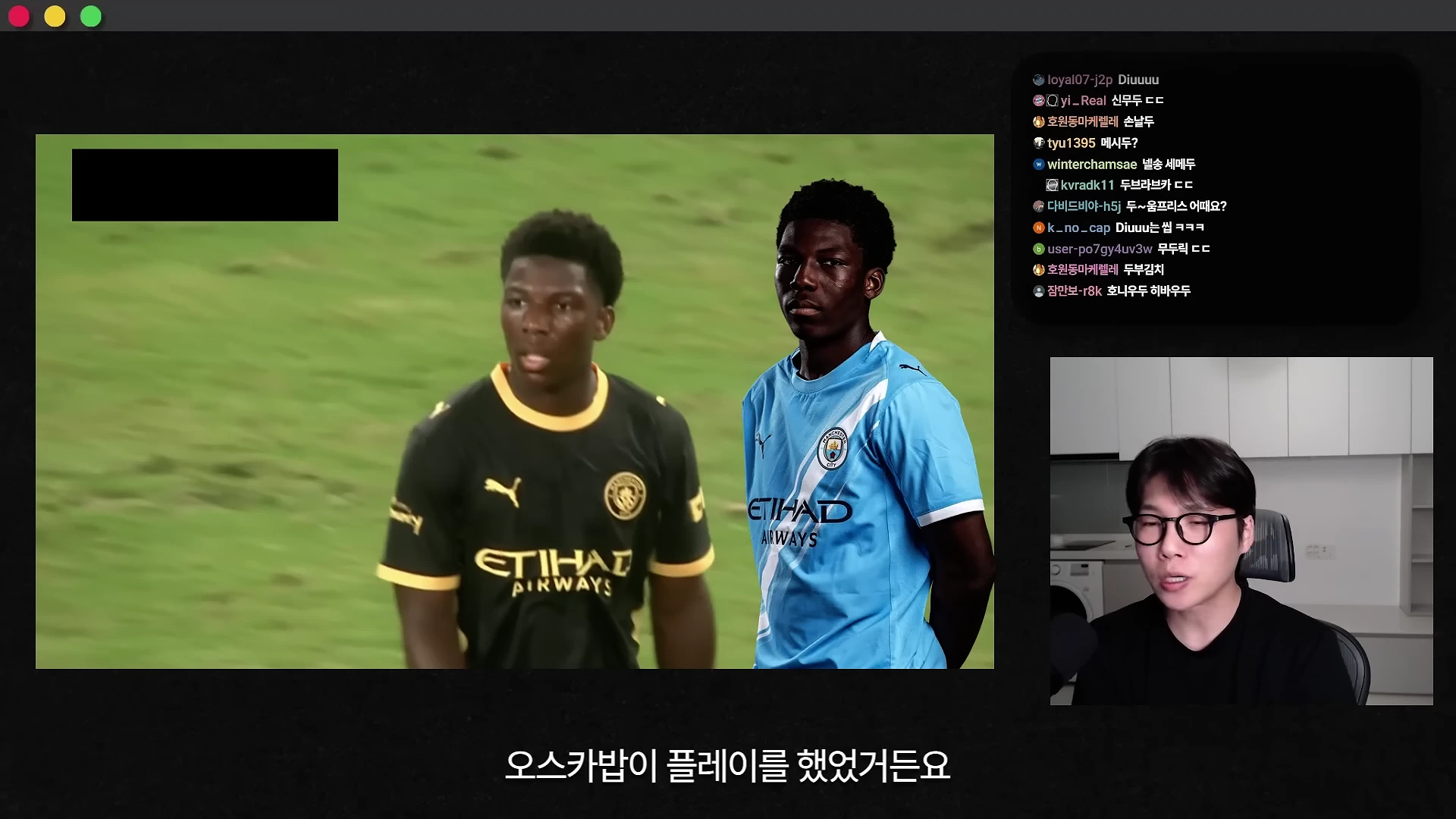 축구 경기 영상을 보여주는 화면과 그 옆에서 설명하고 있는 안경 쓴 남성의 모습이 담긴 유튜브 영상 캡처 화면입니다. 화면 중앙에는 각각 다른 색상의 맨체스터 시티 유니폼을 입은 두 명의 선수가 서 있고, 오른쪽 하단에는 마이크를 낀 남성이 카메라를 보며 이야기하고 있습니다.