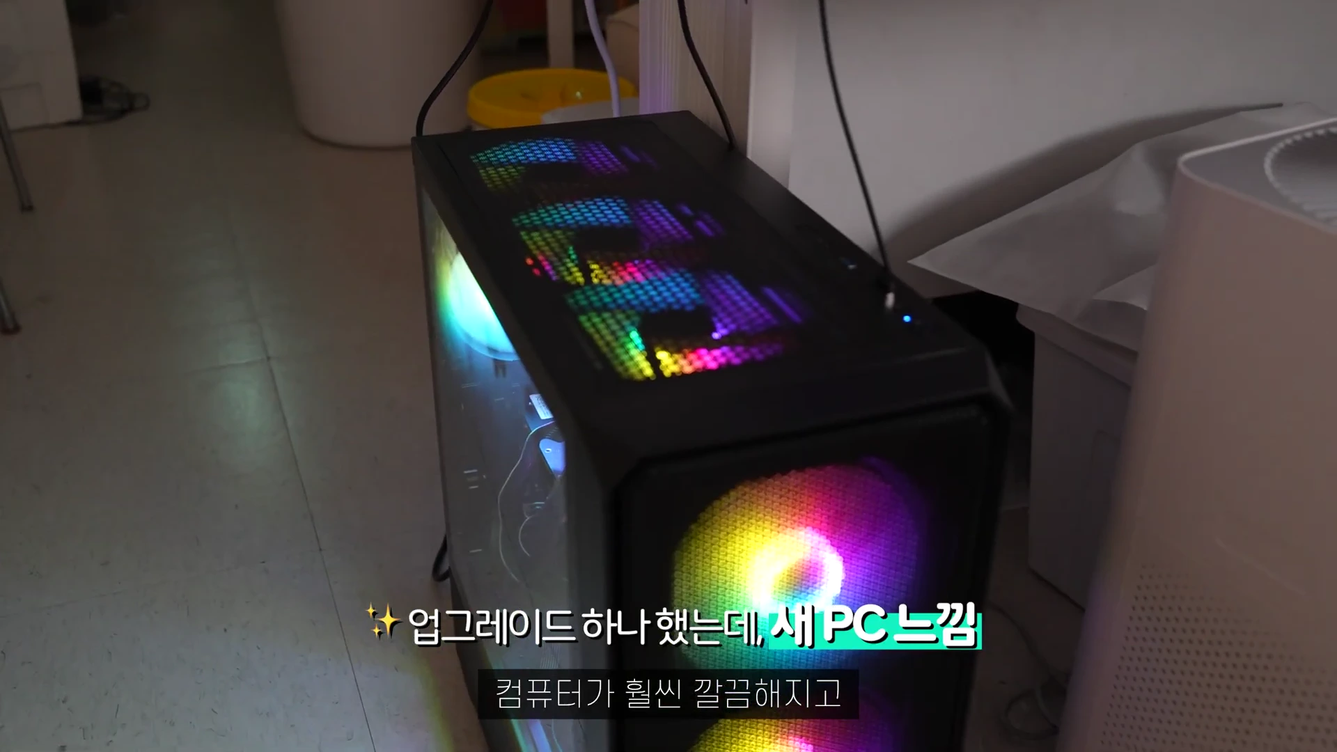 화려한 RGB 조명이 비치는 검은색 PC 케이스가 어두운 방 안에 놓여 있는 모습