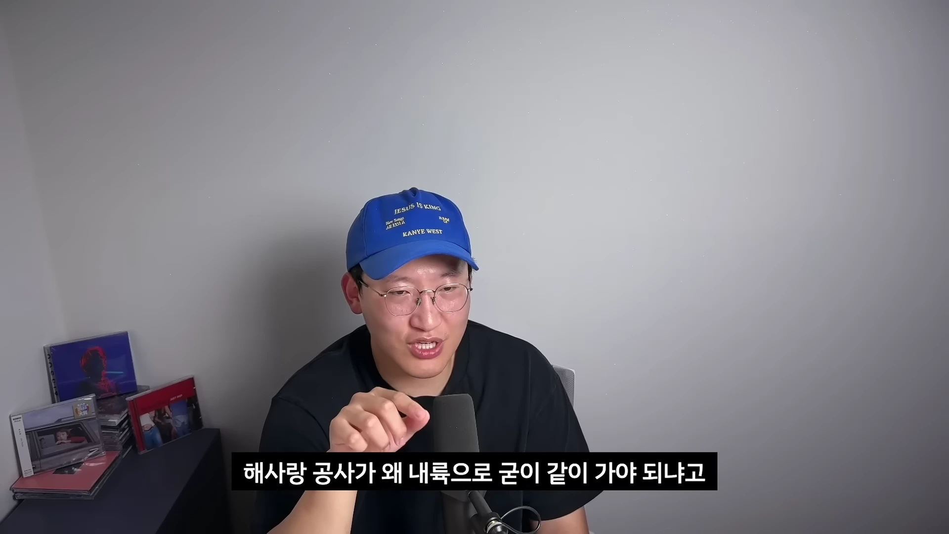 파란색 야구 모자와 안경을 쓴 남성이 마이크 앞에서 손가락으로 가리키며 이야기를 하고 있는 모습. 하단에 자막으로 '해사랑 공사가 왜 내륙으로 굳이 같이 가야 되냐고'라는 문구가 표시되어 있다.