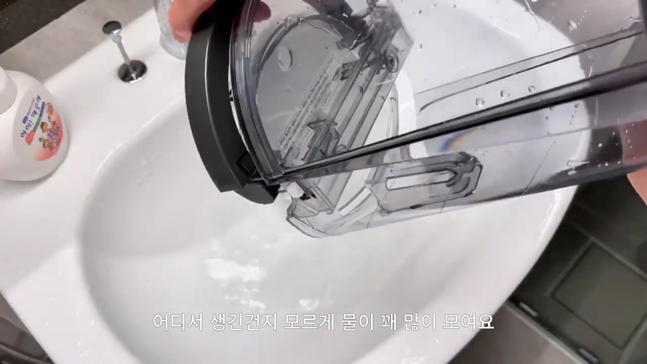 투명한 제습기 물통에서 세면대로 물이 쏟아져 나오는 모습.