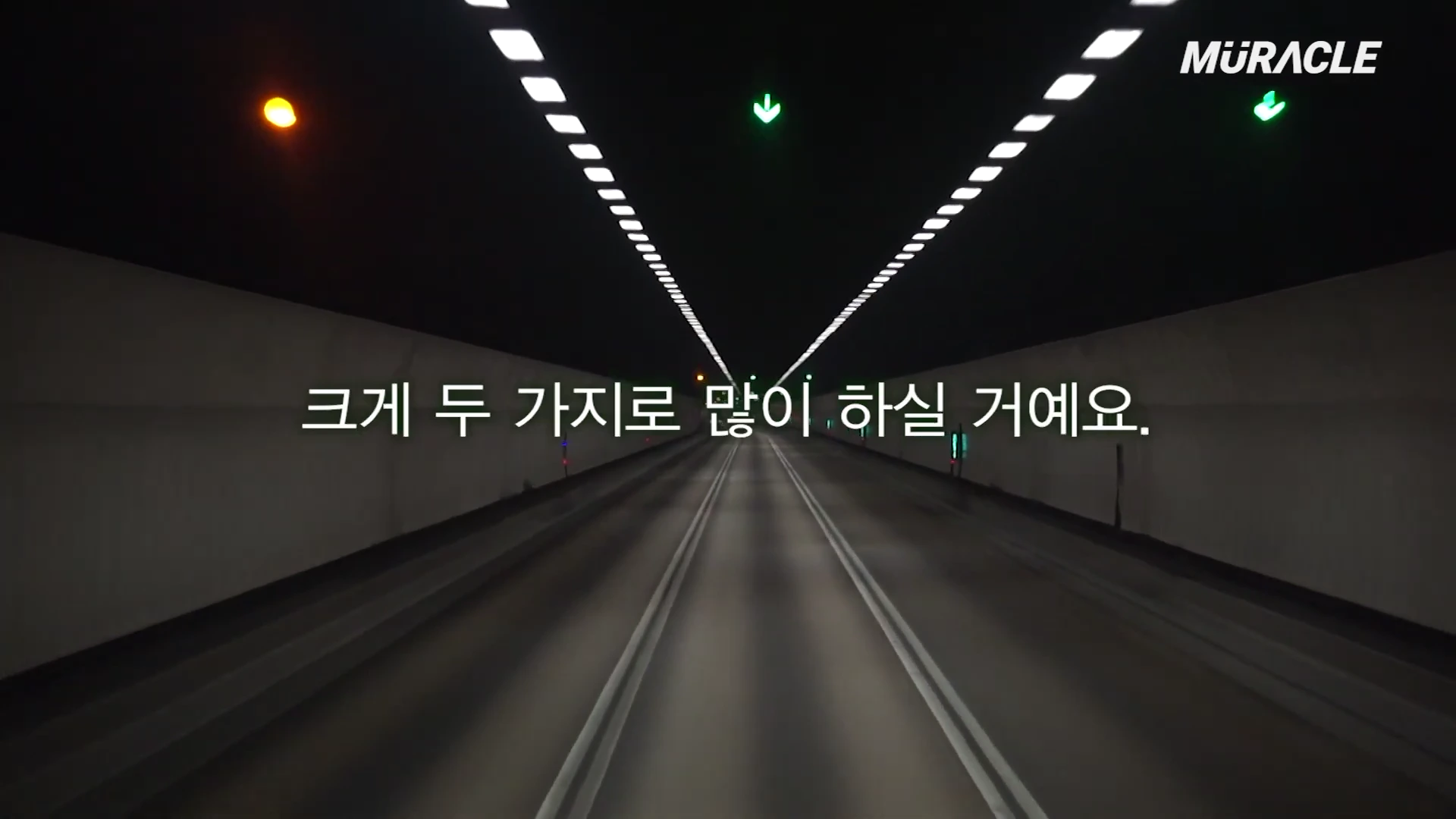 조명이 켜진 어두운 터널 내부를 정면으로 바라보는 시점의 영상 화면입니다.