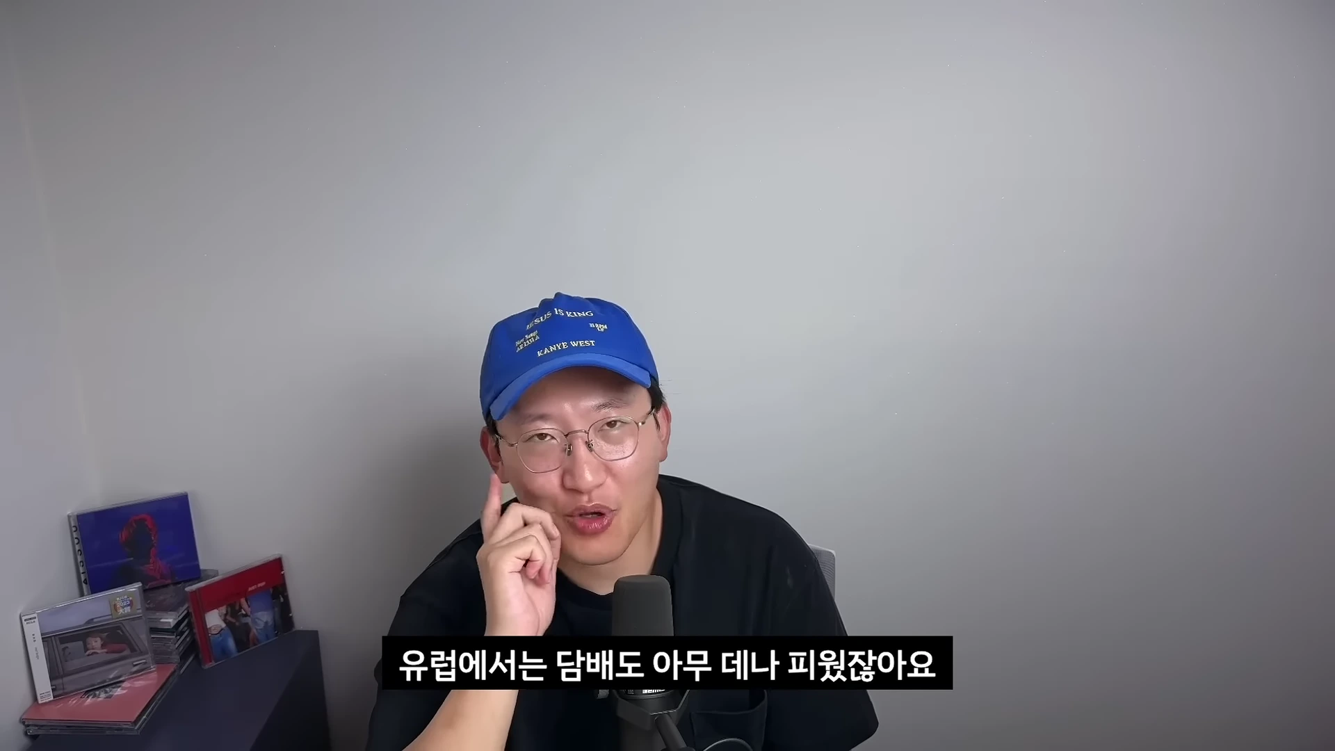 파란색 야구 모자와 안경을 쓴 남성이 마이크 앞에 앉아 정면을 보며 이야기를 하는 모습이다.