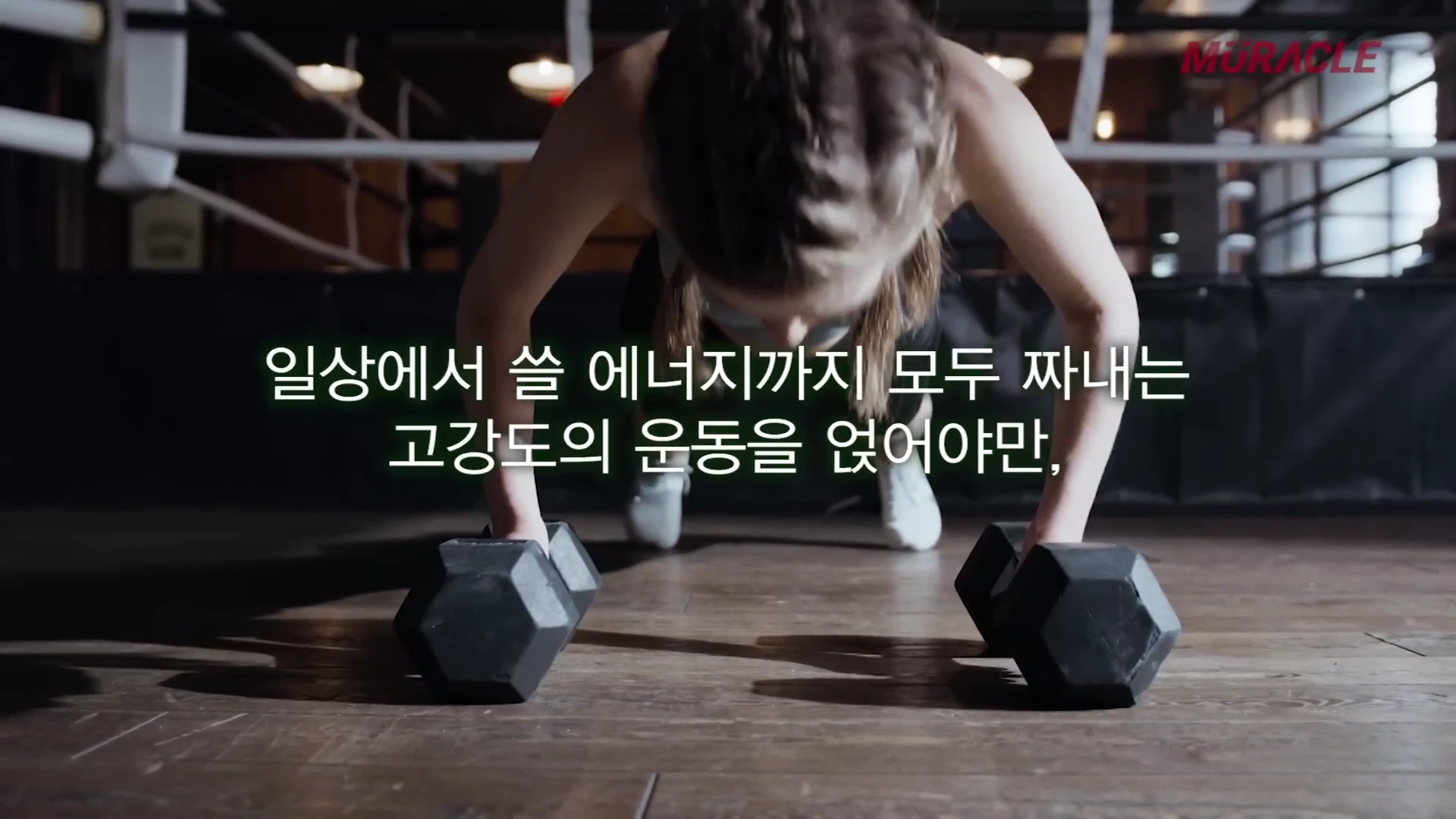 복싱 링 위에서 덤벨을 짚고 푸시업을 하는 사람의 상반신과 그 위에 '일상에서 쓸 에너지까지 모두 짜내는 고강도의 운동을 얹어야만'이라는 자막이 적힌 영상 화면