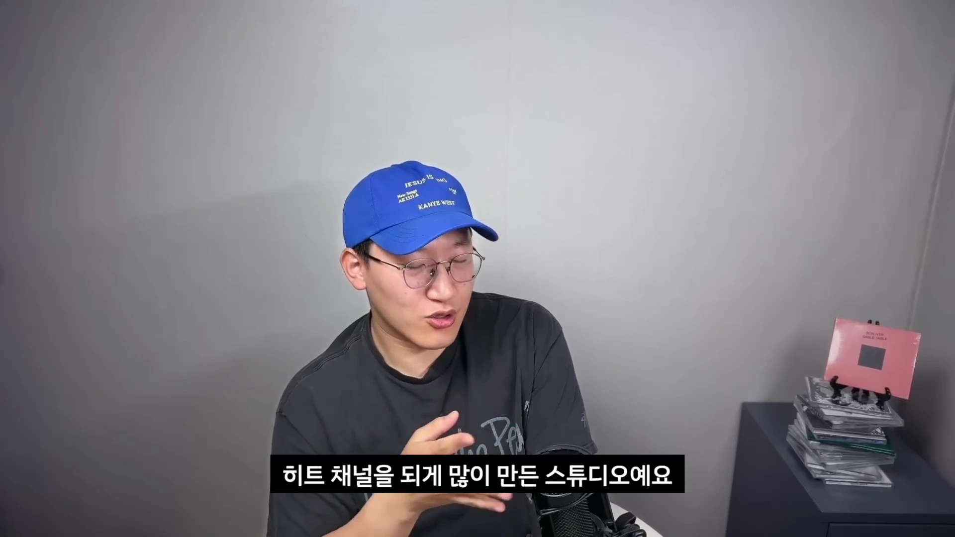 파란색 야구 모자와 안경을 쓴 남성이 마이크 앞에서 대화하는 상반신 모습의 영상 화면