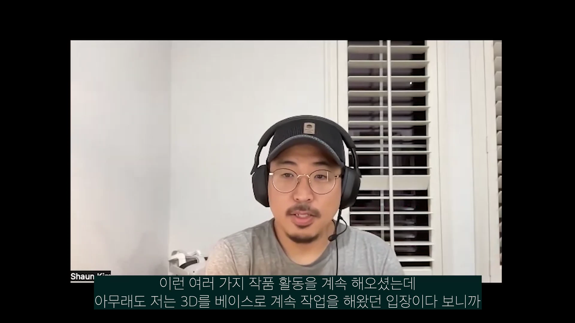 안경과 검은색 모자를 착용한 남성이 헤드셋을 쓰고 정면을 응시하며 이야기하는 모습이 담긴 화상 회의 화면