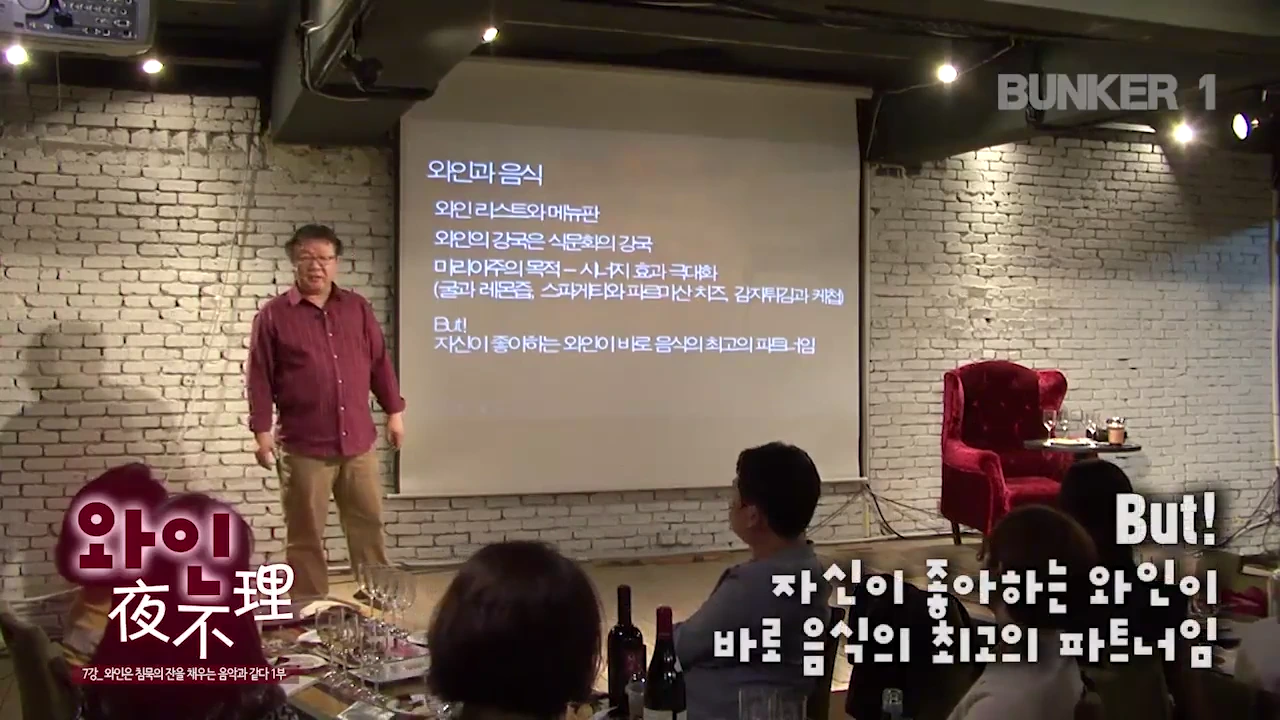 강단에서 와인 강의를 진행하는 남성 강사와 그를 바라보는 청중, 그리고 '와인과 음식'에 관한 내용이 적힌 스크린이 보입니다.