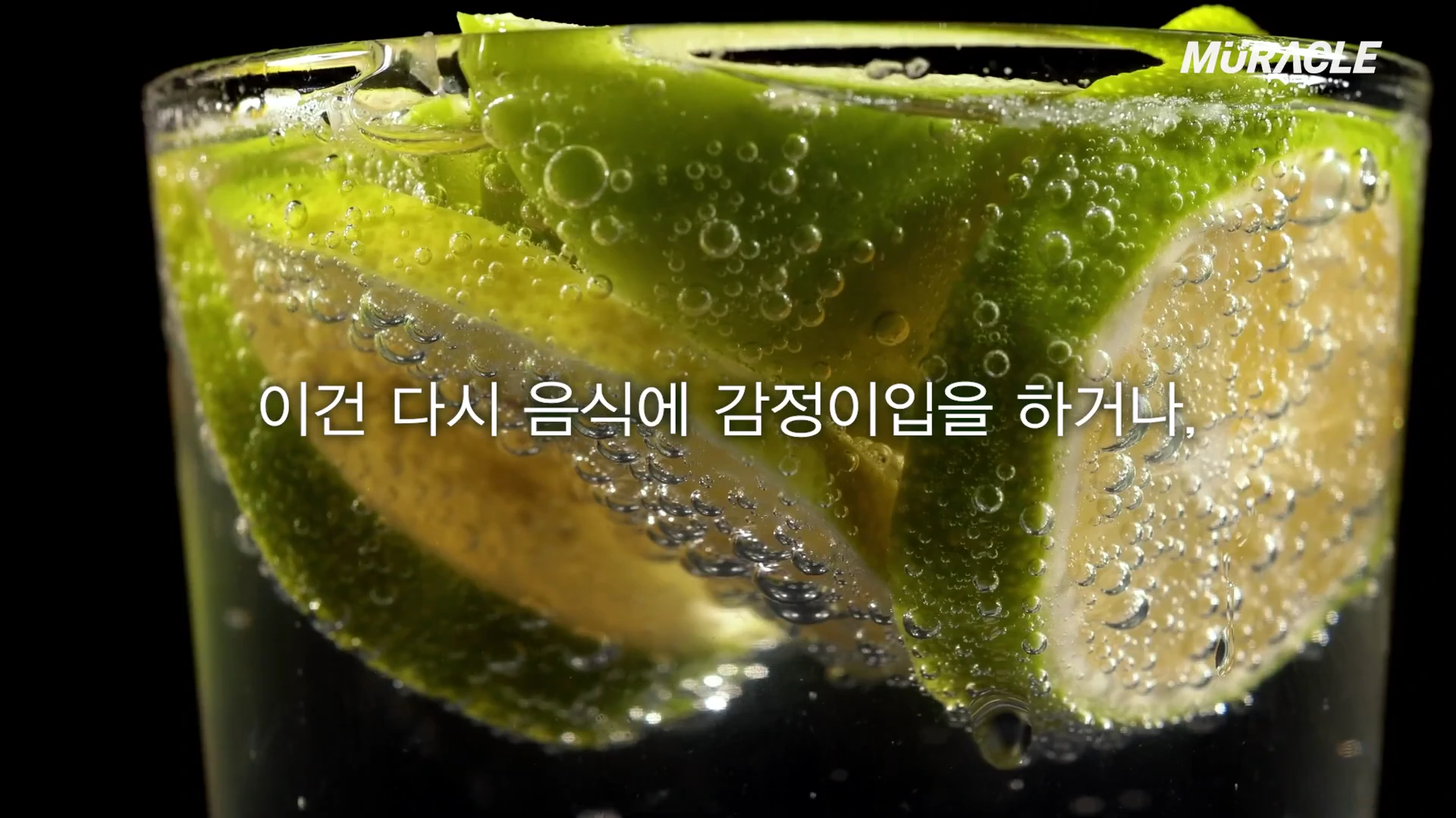 투명한 유리잔에 담긴 탄산수 속에 초록색 라임 슬라이스가 들어있고, 중앙에 흰색 한국어 자막이 겹쳐져 있습니다.