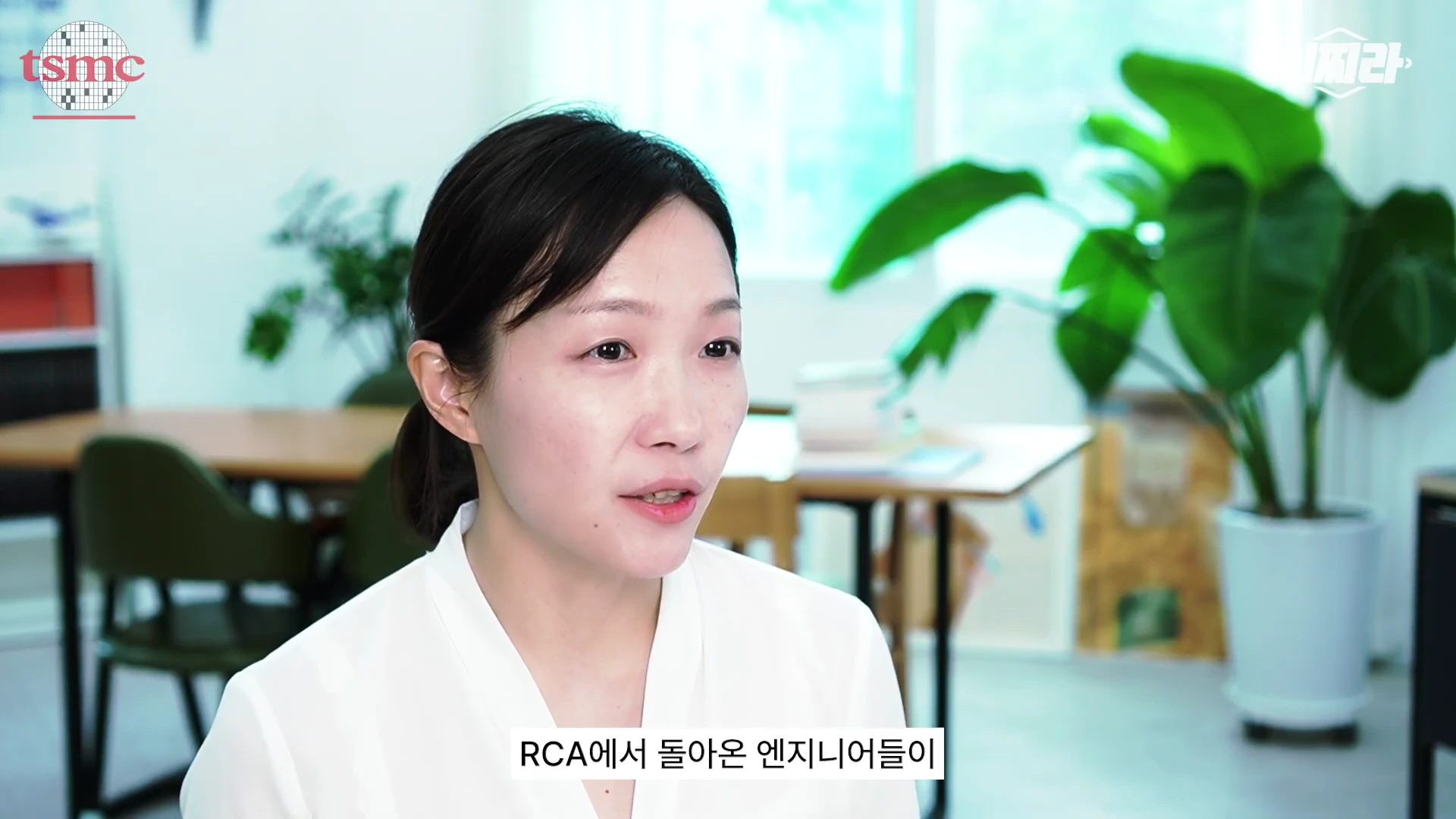 흰색 상의를 입은 여성이 밝은 실내 사무 공간에서 인터뷰를 진행하고 있는 모습