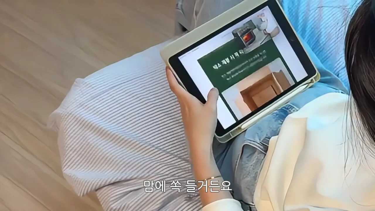 태블릿 PC 화면에 에어프라이어 상세 페이지가 떠 있고 이를 손으로 잡고 있는 모습