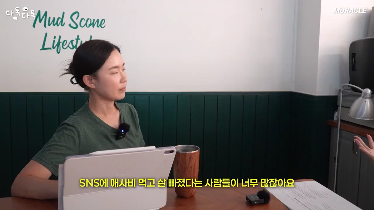 초록색 티셔츠를 입은 여성이 테이블 앞에 앉아 이야기를 나누고 있는 모습으로, 화면 하단에는 다이어트 관련 자막이 노란색으로 표시되어 있습니다.