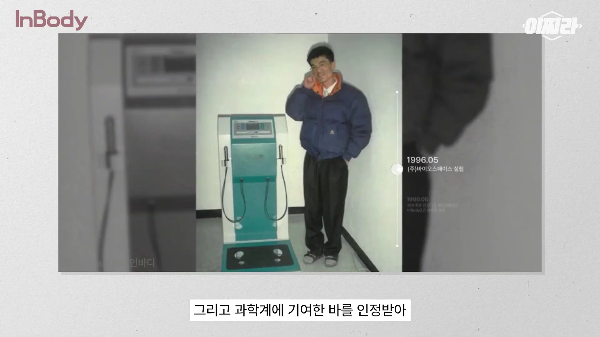 1990년대 초반 스타일의 옷을 입은 남성이 초기 체성분 분석기 옆에 서서 포즈를 취하고 있는 옛 사진이 담긴 화면