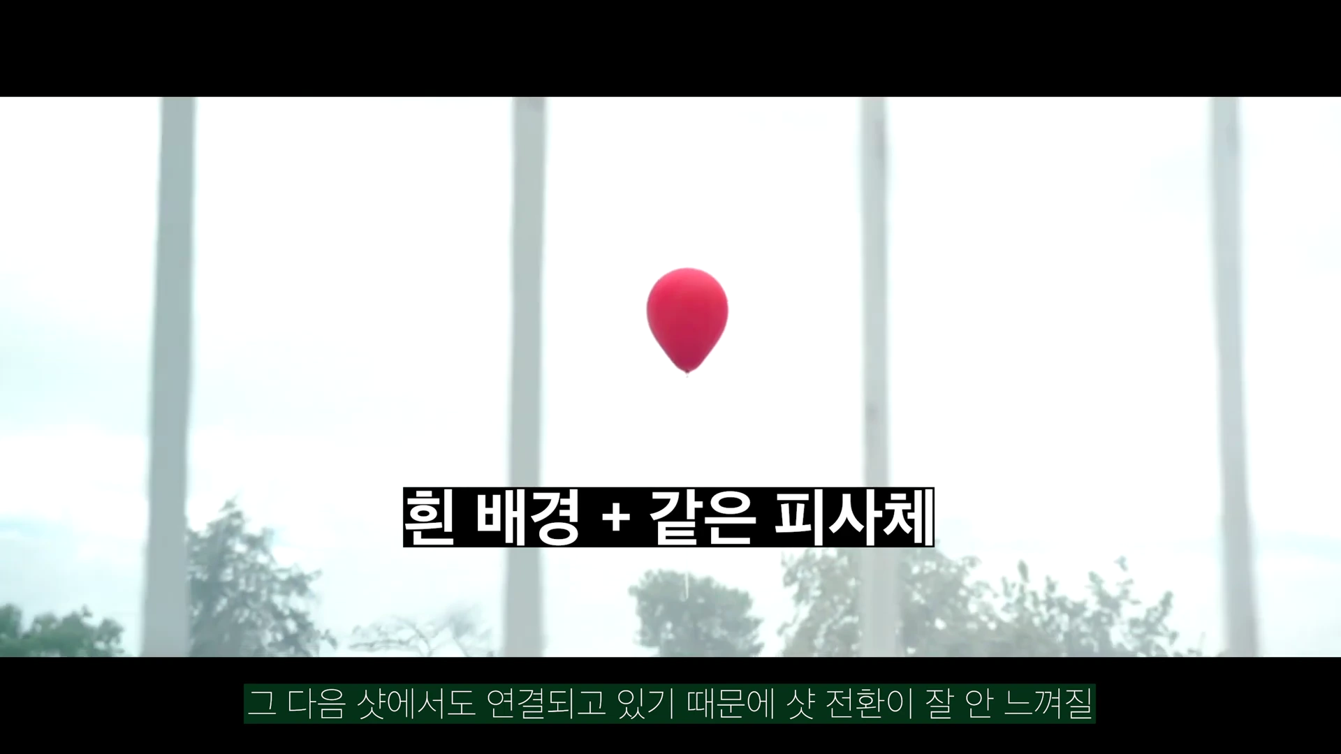 영화 장면 속 밝고 흐린 하늘을 배경으로 빨간 풍선 하나가 떠 있고 그 아래 흰 배경 + 같은 피사체라는 검은색 자막이 배치되어 있는 영상 프레임입니다.