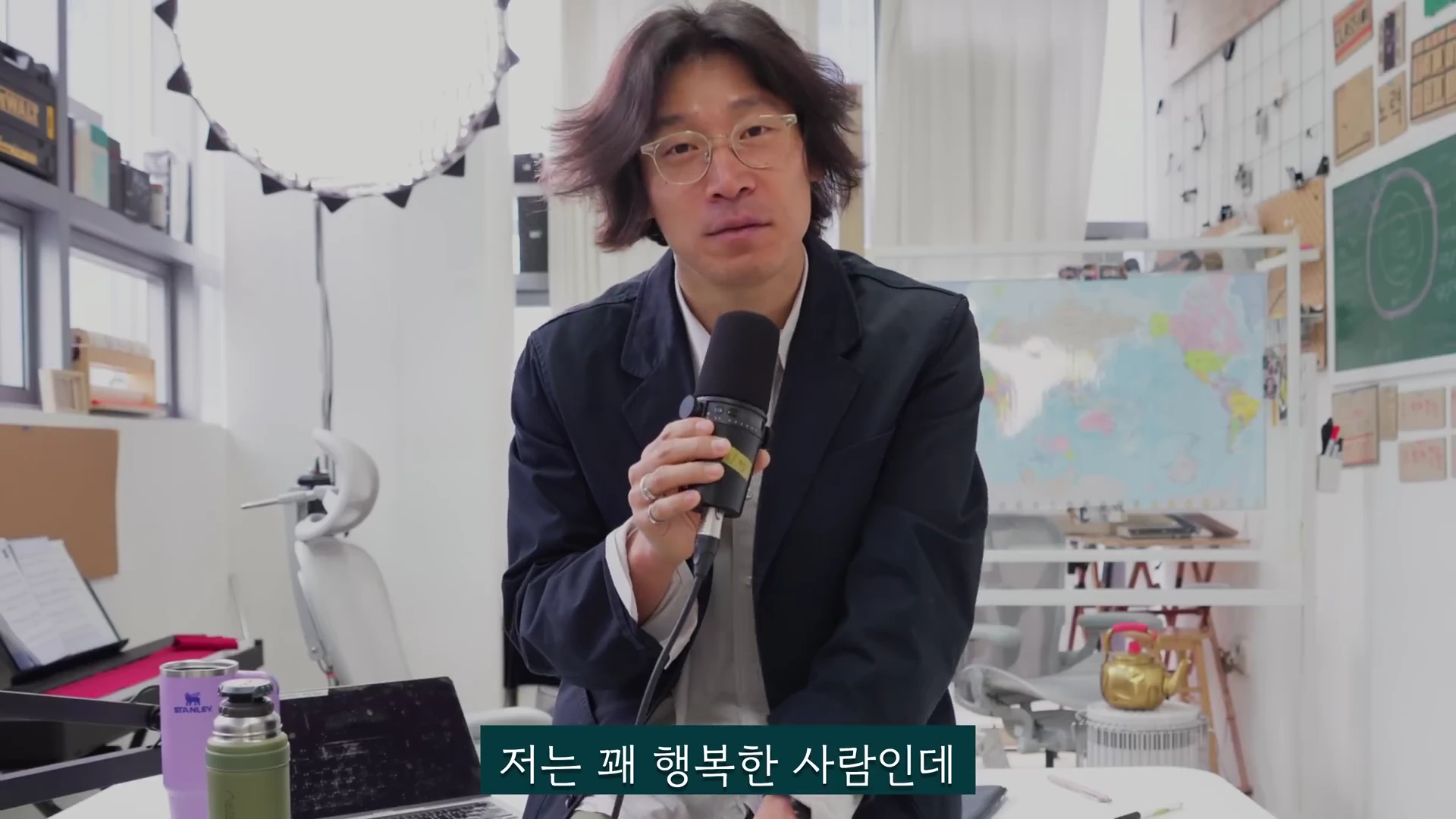 안경을 쓴 남성이 마이크를 잡고 이야기를 나누는 스튜디오 내부 모습