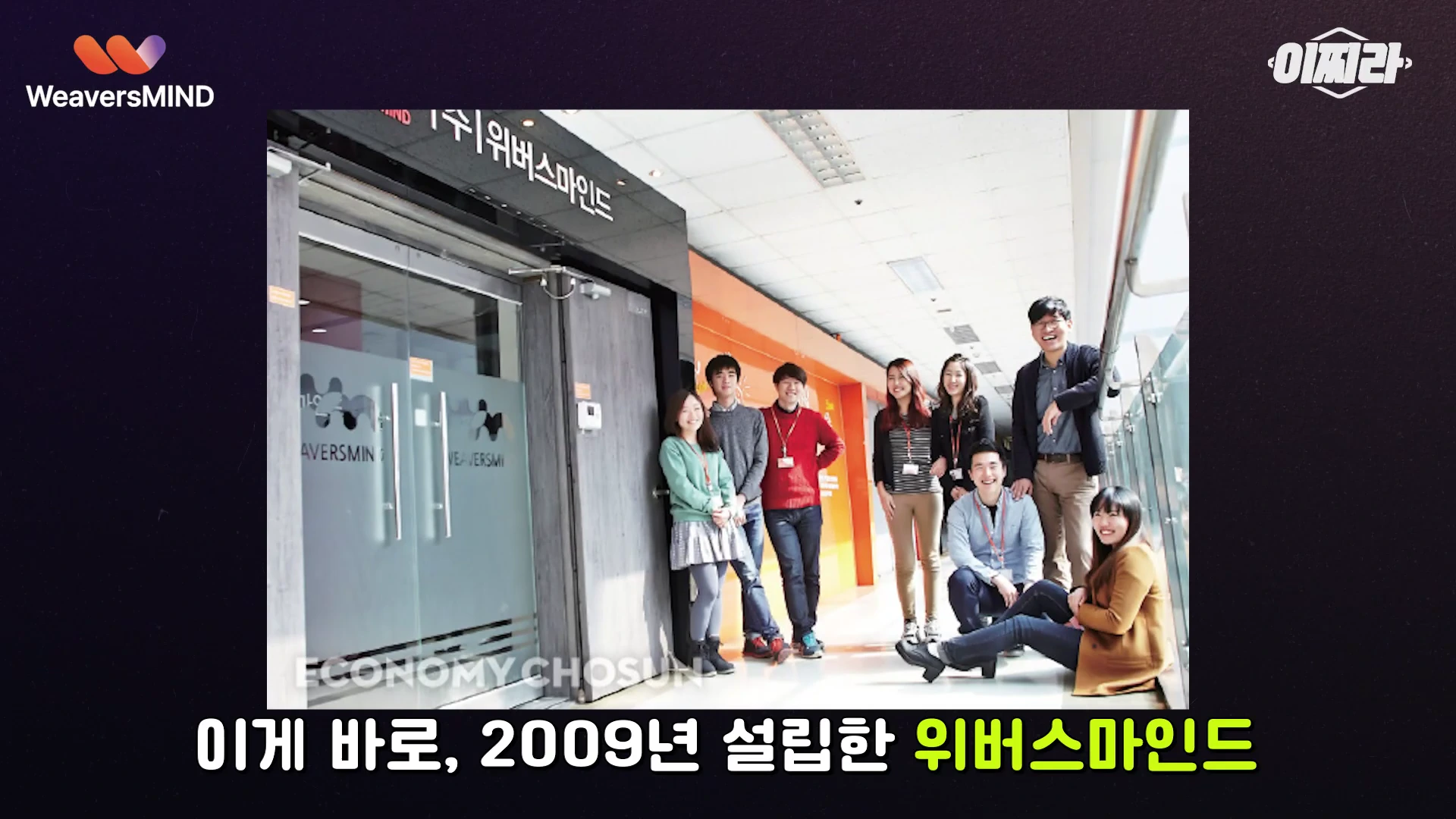 기업 사무실 입구 앞에서 밝게 웃으며 서 있는 직원들의 단체 사진
