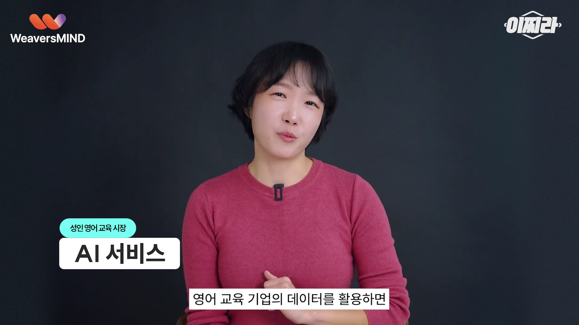 단발머리의 여성 출연자가 검은색 배경 앞에서 붉은색 상의를 입고 정면을 바라보며 이야기하고 있으며, 화면 하단에는 '성인 영어 교육 시장 AI 서비스'라는 자막이 표시되어 있다.