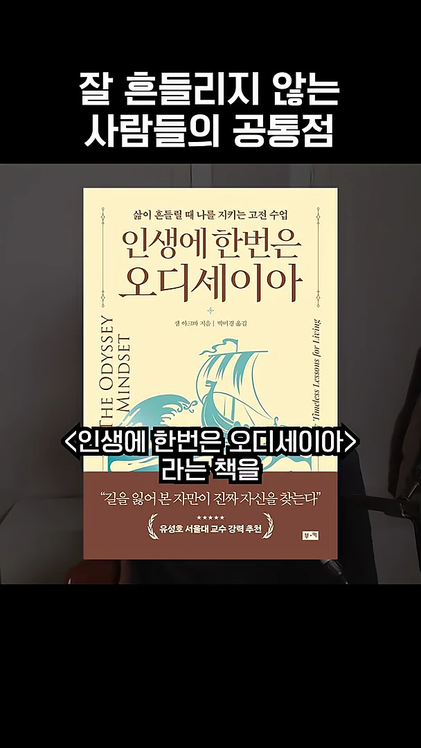 영상 화면 중앙에 '인생에 한번은 오디세이아'라는 책 표지가 크게 배치되어 있고, 상단에는 '잘 흔들리지 않는 사람들의 공통점'이라는 문구가, 하단에는 '인생에 한번은 오디세이아라는 책을'이라는 자막이 떠 있습니다.