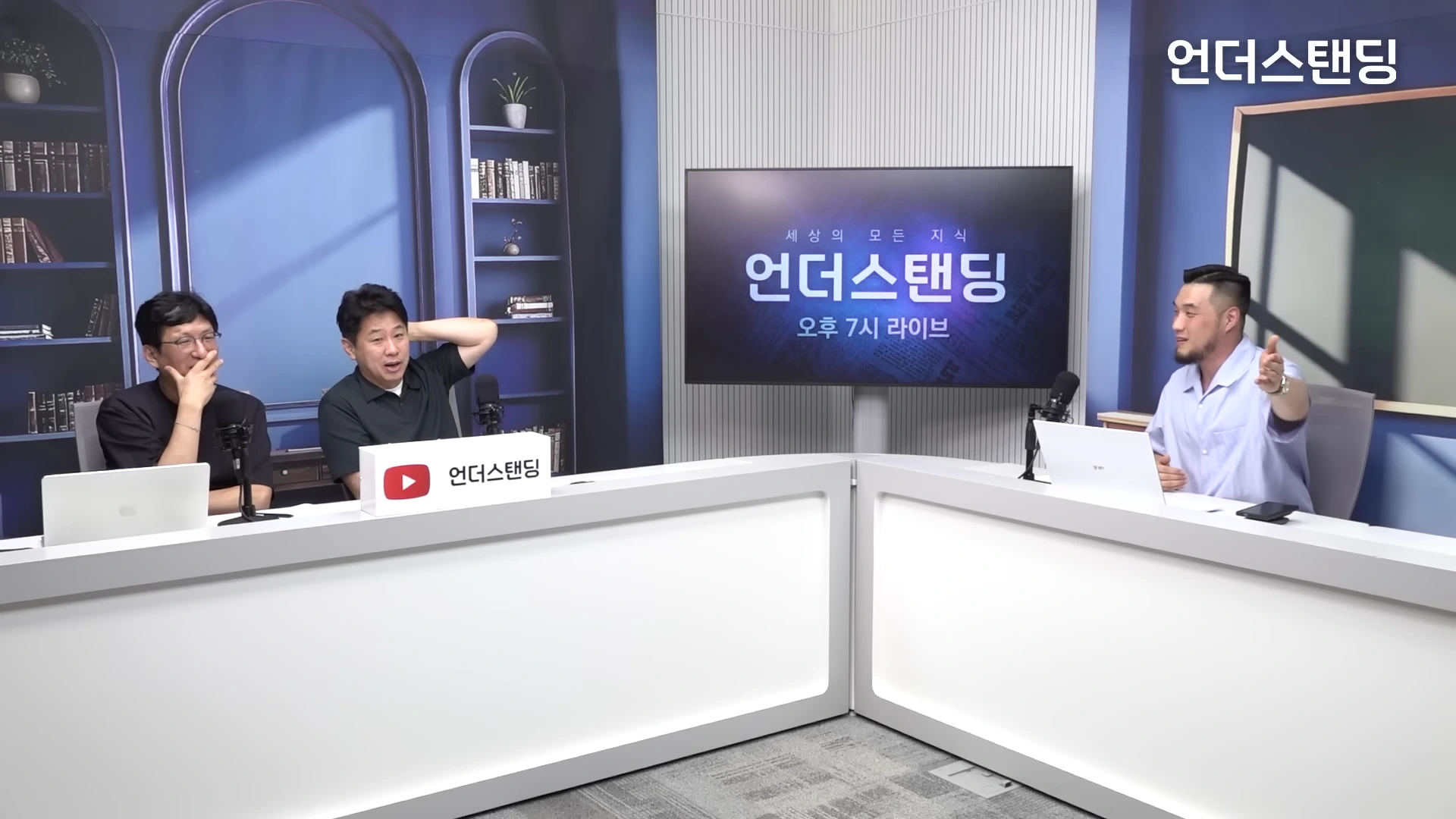 세 명의 남성이 파란색 배경의 스튜디오에서 책상에 앉아 대화를 나누고 있는 모습으로, 중앙에 있는 대형 화면에는 프로그램 제목이 적혀 있다.