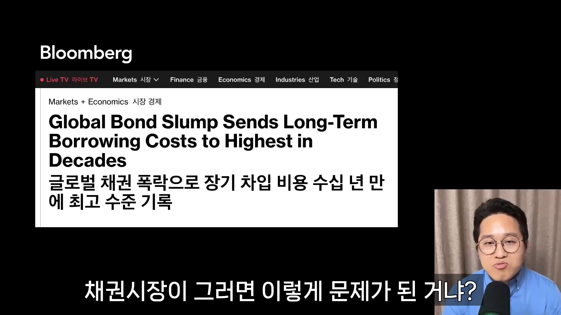 블룸버그 뉴스 기사 헤드라인이 화면 상단에 크게 보이고, 우측 하단에는 안경을 쓴 남성이 마이크 앞에 앉아 있는 모습이 담긴 화면입니다.