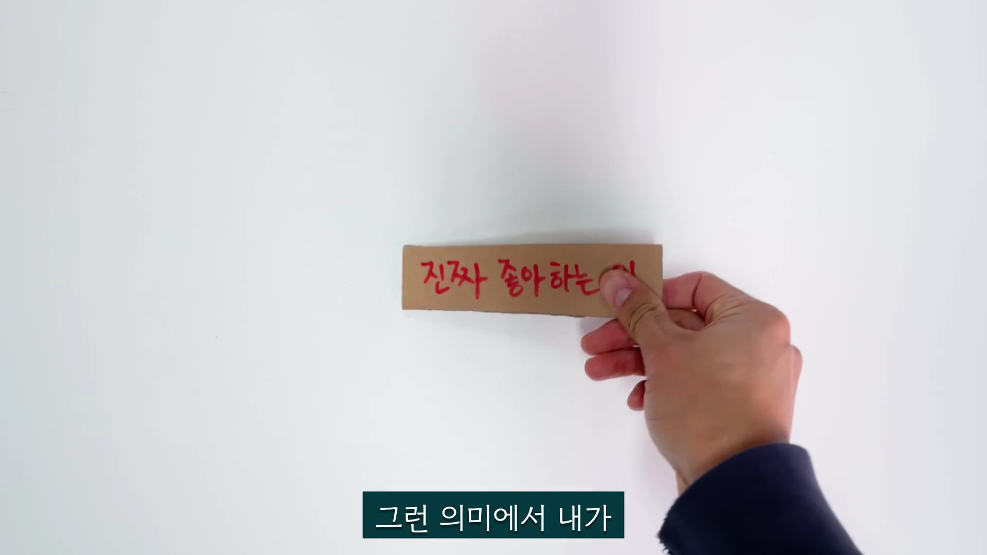 흰색 배경 위에서 한 사람의 손이 '진짜 좋아하는 일'이라고 빨간색 글씨가 적힌 작은 종이 조각을 들고 있다.