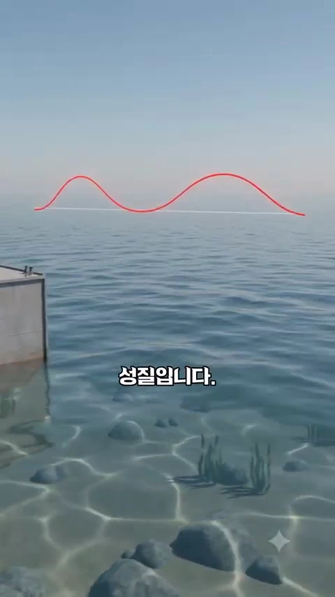 바다 수면 위로 붉은색 파형 그래프가 그려져 있고, 화면 왼쪽에는 콘크리트 구조물의 일부가 보이며, 맑은 바닷속 바닥의 돌과 해초가 비치는 그래픽 영상