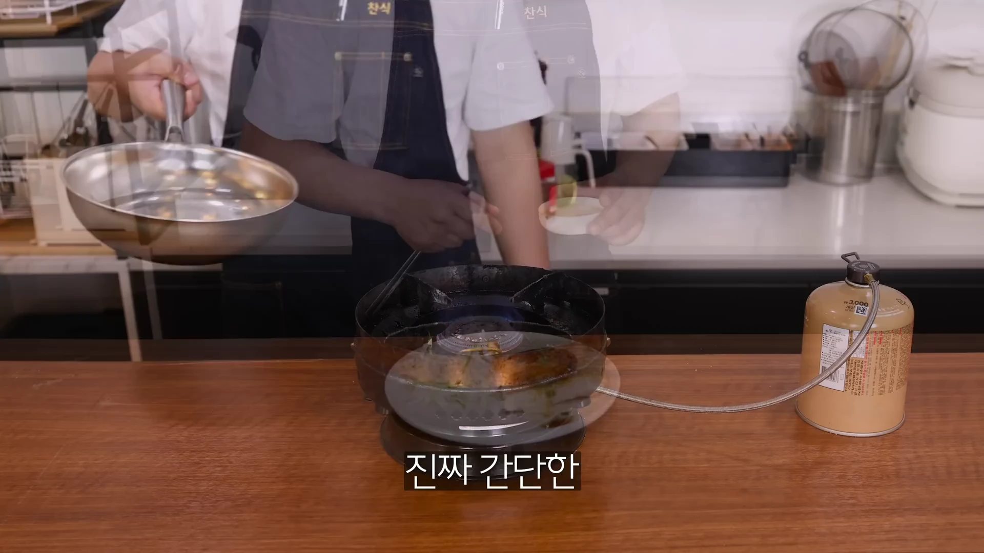 요리사가 가스 버너 위에 놓인 프라이팬에서 항정살을 굽고 있는 모습