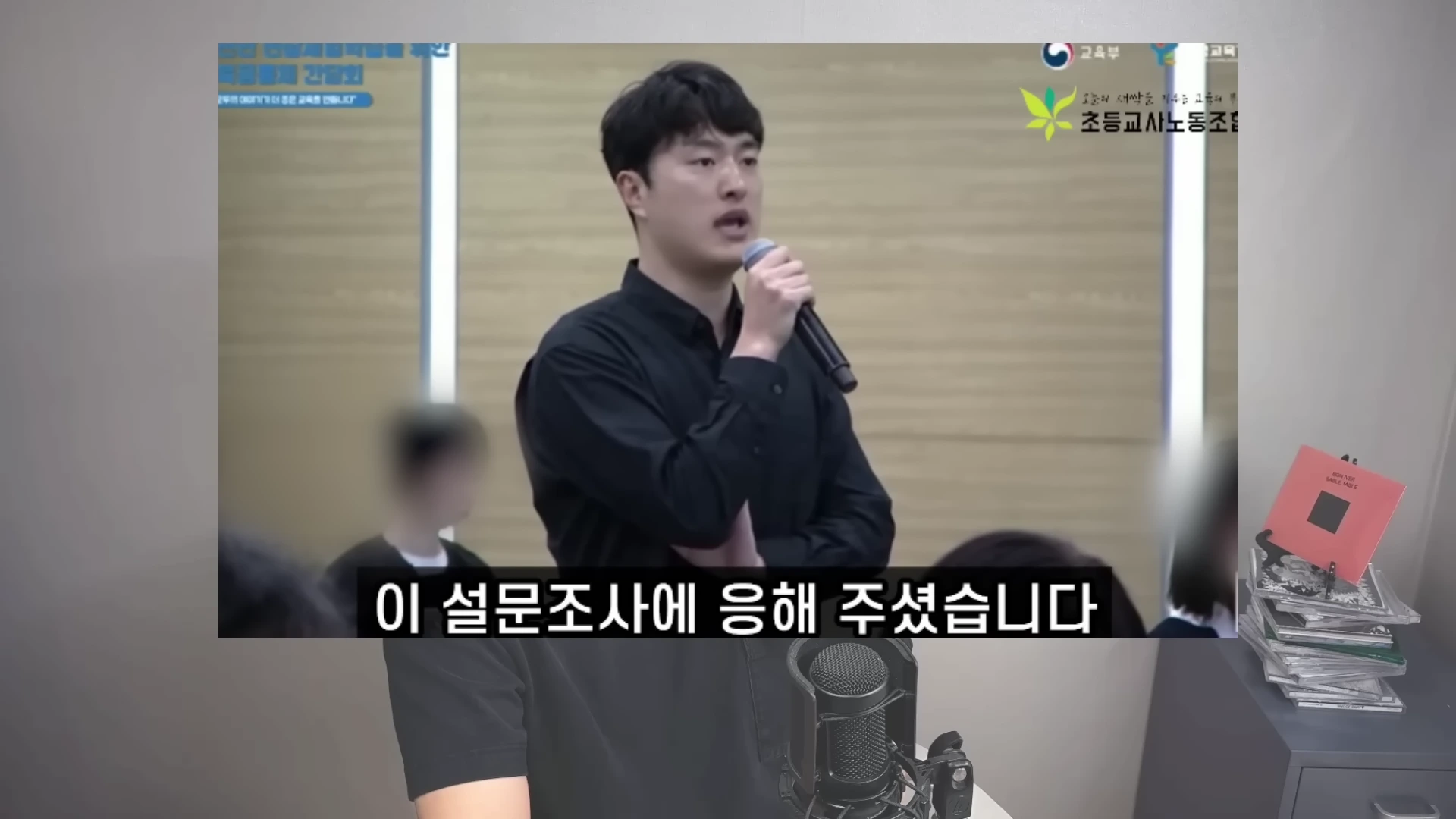 마이크를 잡고 진지하게 발언하는 남성과 그 아래 '이 설문조사에 응해 주셨습니다'라는 자막이 달린 영상 화면