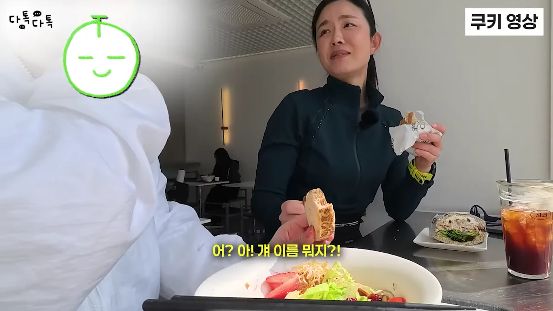 카페 테이블에 앉아 샐러드와 샌드위치를 먹으며 대화 중인 두 사람의 모습이 담긴 영상 캡처 화면
