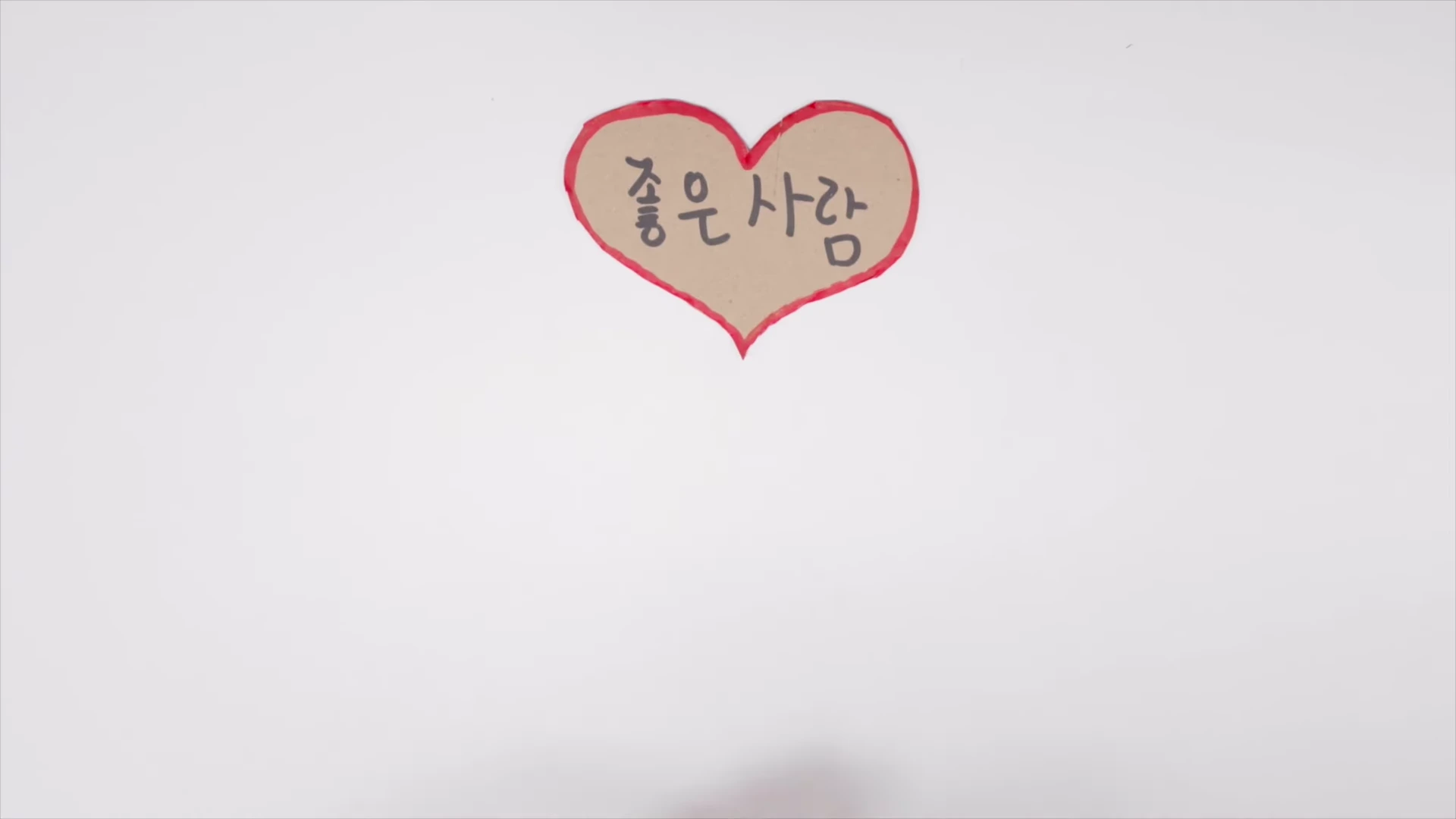 흰색 배경 중앙에 빨간 테두리의 하트 모양 종이가 붙어 있고 그 안에 '좋은 사람'이라는 글씨가 적혀 있다.
