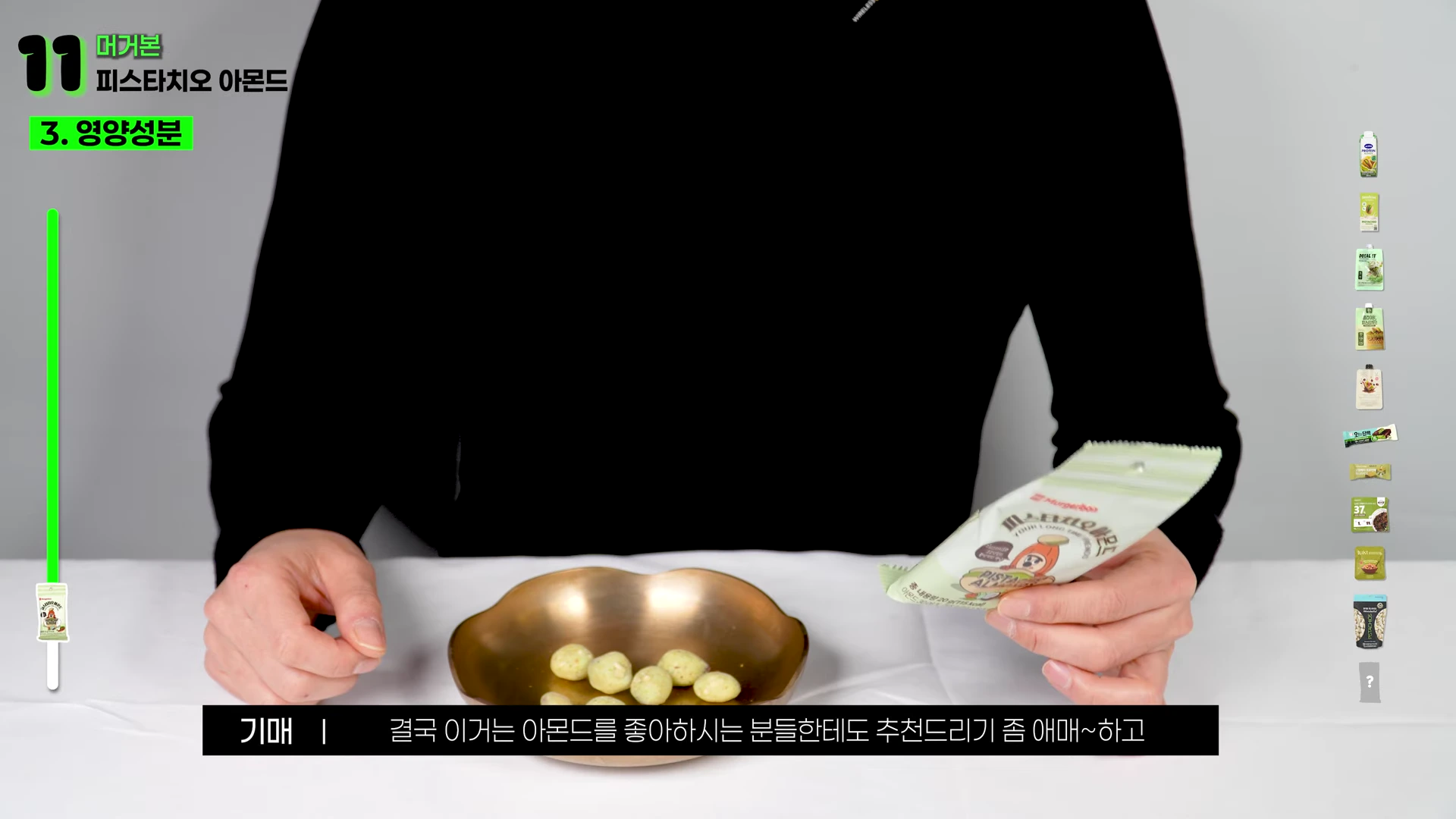 검은색 상의를 입은 사람이 피스타치오 아몬드 제품 패키지를 들고 있으며, 앞에는 유기 그릇에 담긴 아몬드 몇 알이 놓여 있는 모습.