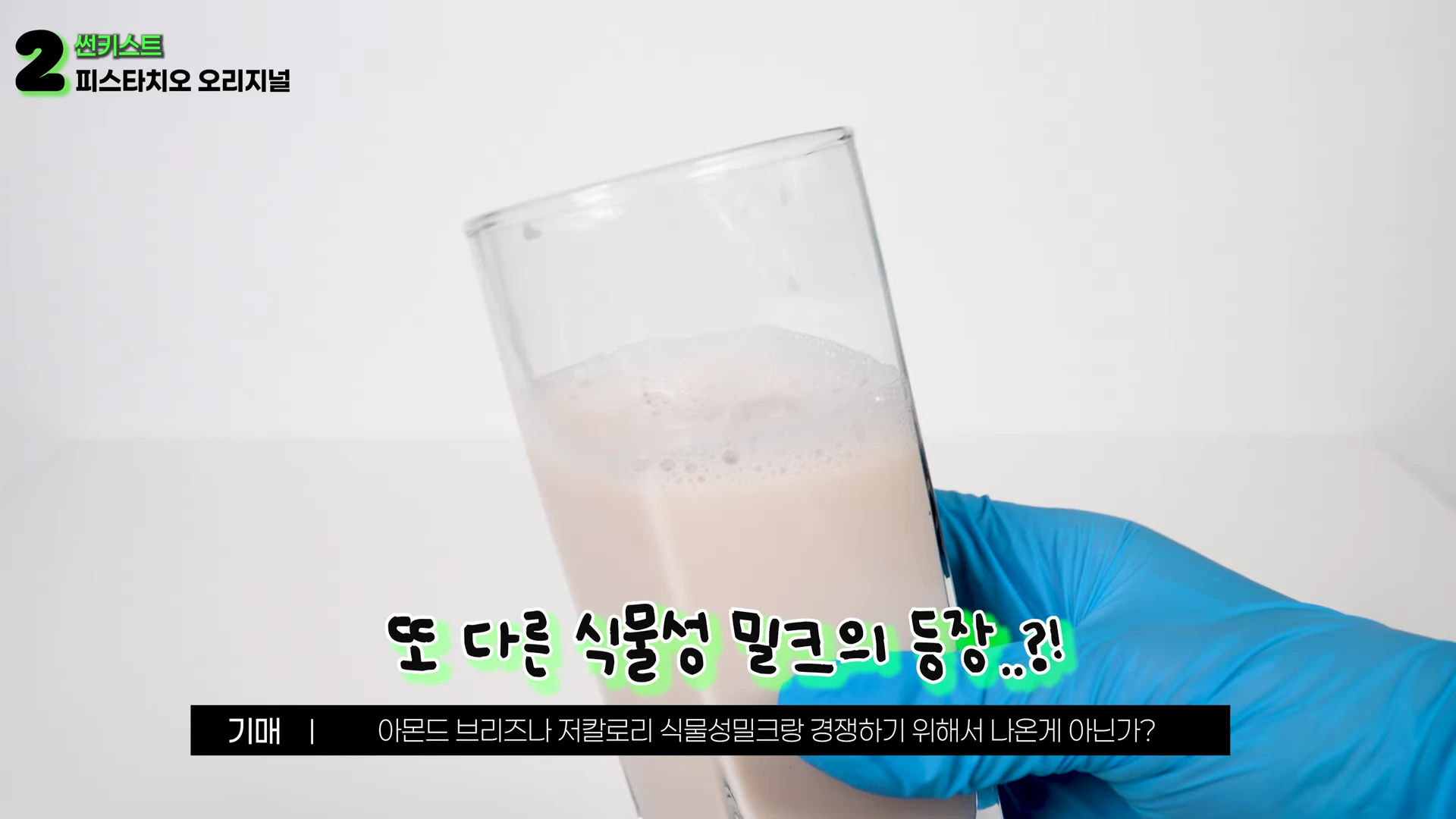 푸른색 위생 장갑을 낀 손이 피스타치오 음료가 담긴 유리컵을 들고 있는 모습으로, 화면 상단에 제품명과 하단에 자막이 배치되어 있습니다.