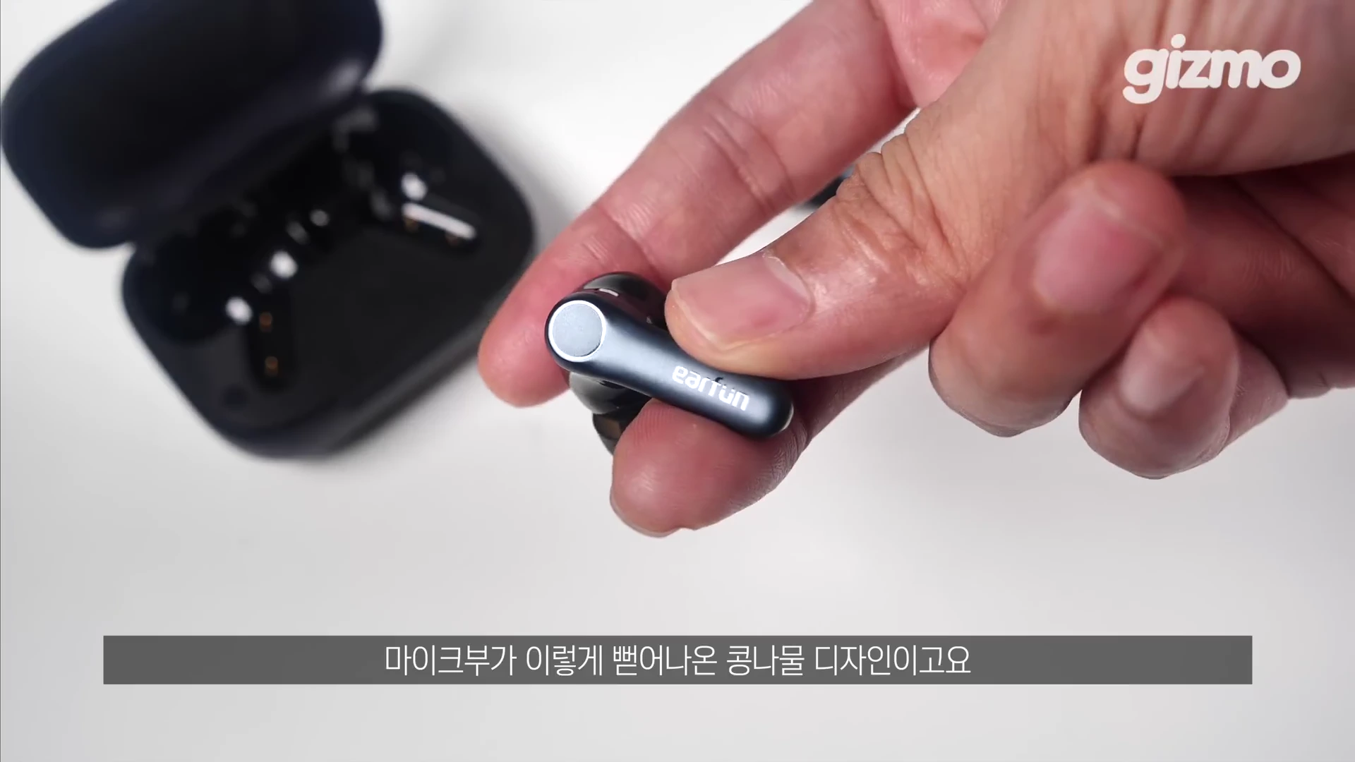 손으로 에어펀(EarFun) 브랜드 로고가 새겨진 무선 이어버드를 들고 있으며, 배경에는 열려 있는 충전 케이스가 놓여 있는 모습입니다.